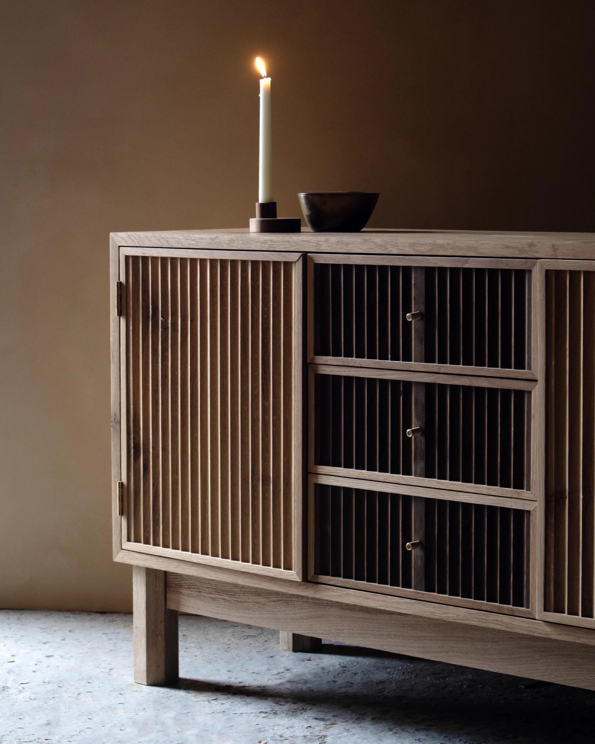 Handcrafted Flauta cabinet in solid oak with fluted front panels, natural and fumed oak contrast, brass detailing, and octagonal legs