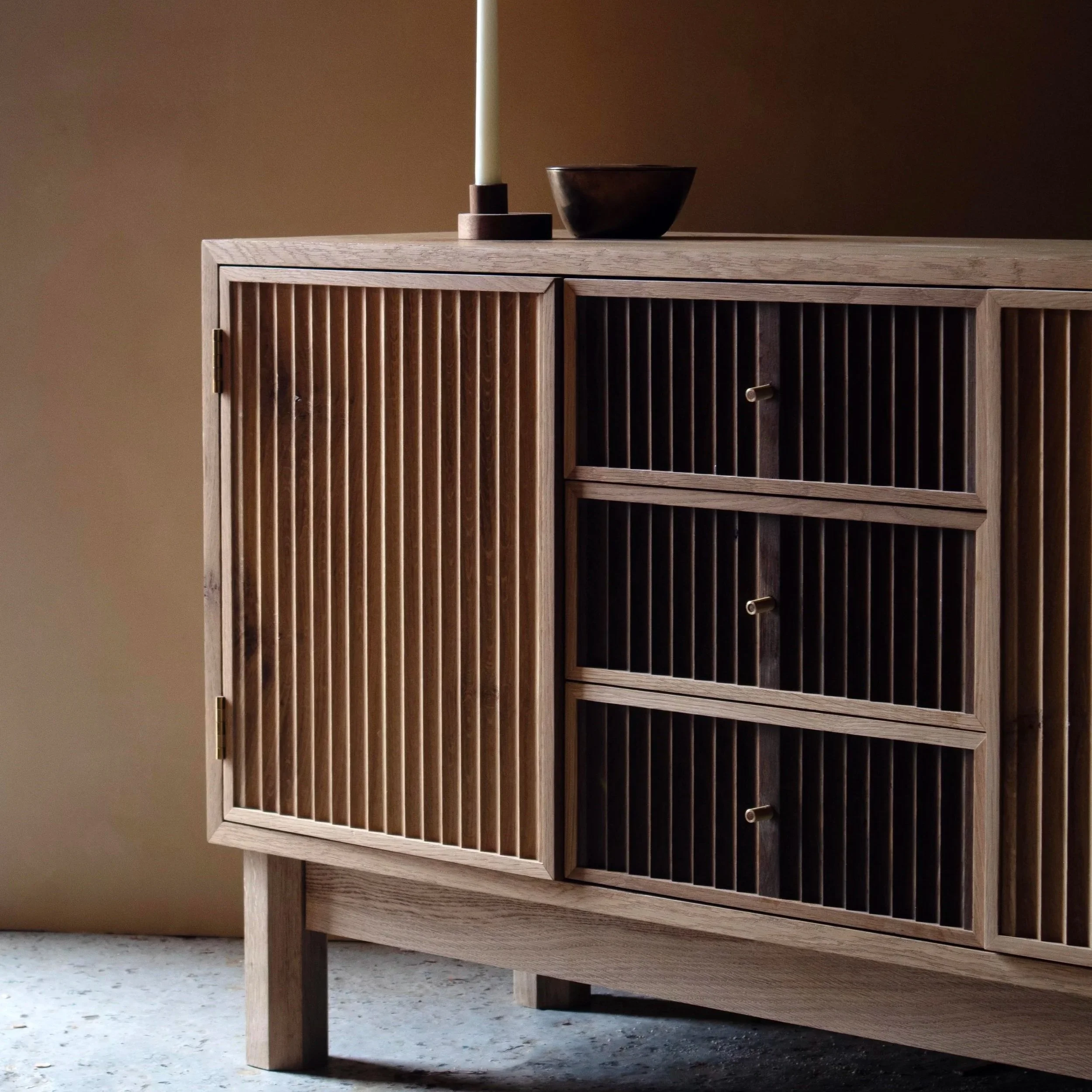 Handcrafted Flauta cabinet in solid oak with fluted front panels, natural and fumed oak contrast, brass detailing, and octagonal legs