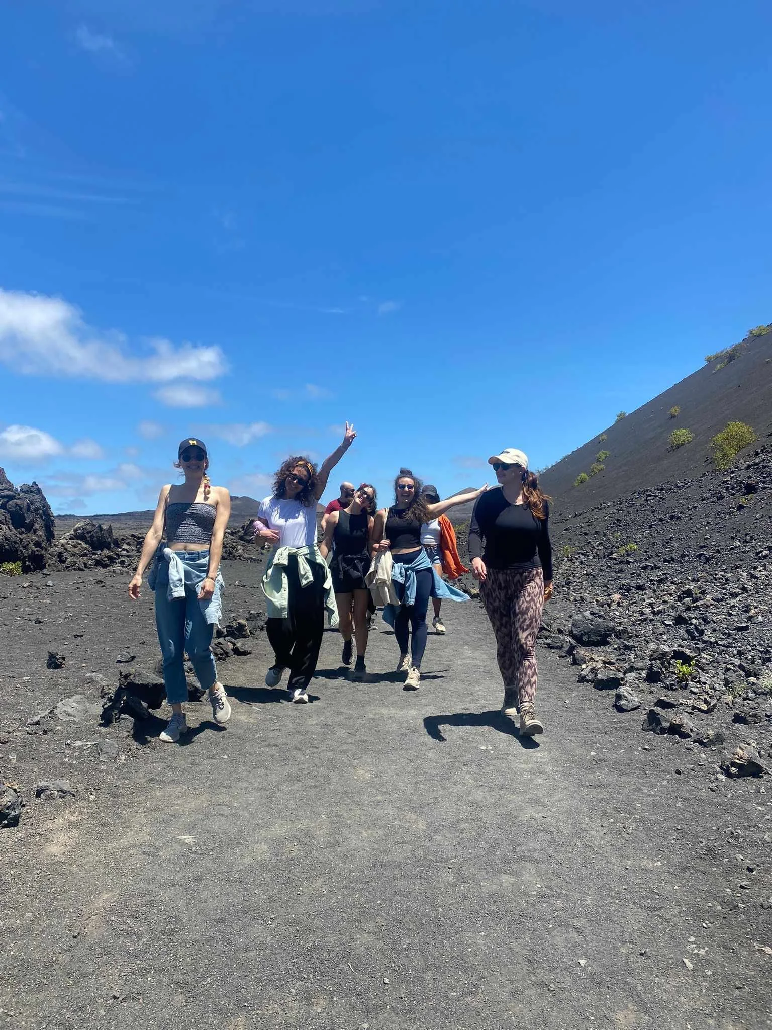 Group of eight women hiking on a volcanic landscape with a bright blue sky