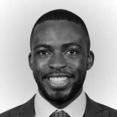Black man in business suit smiling, in black and white.