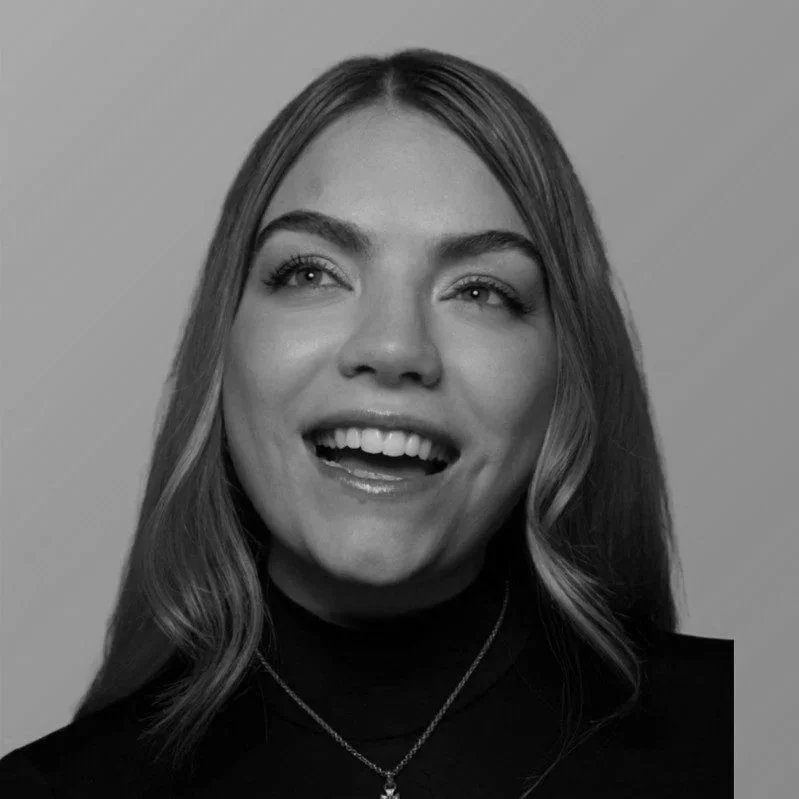 Black and white photo of a young woman with styled hair, smiling and looking slightly upward.