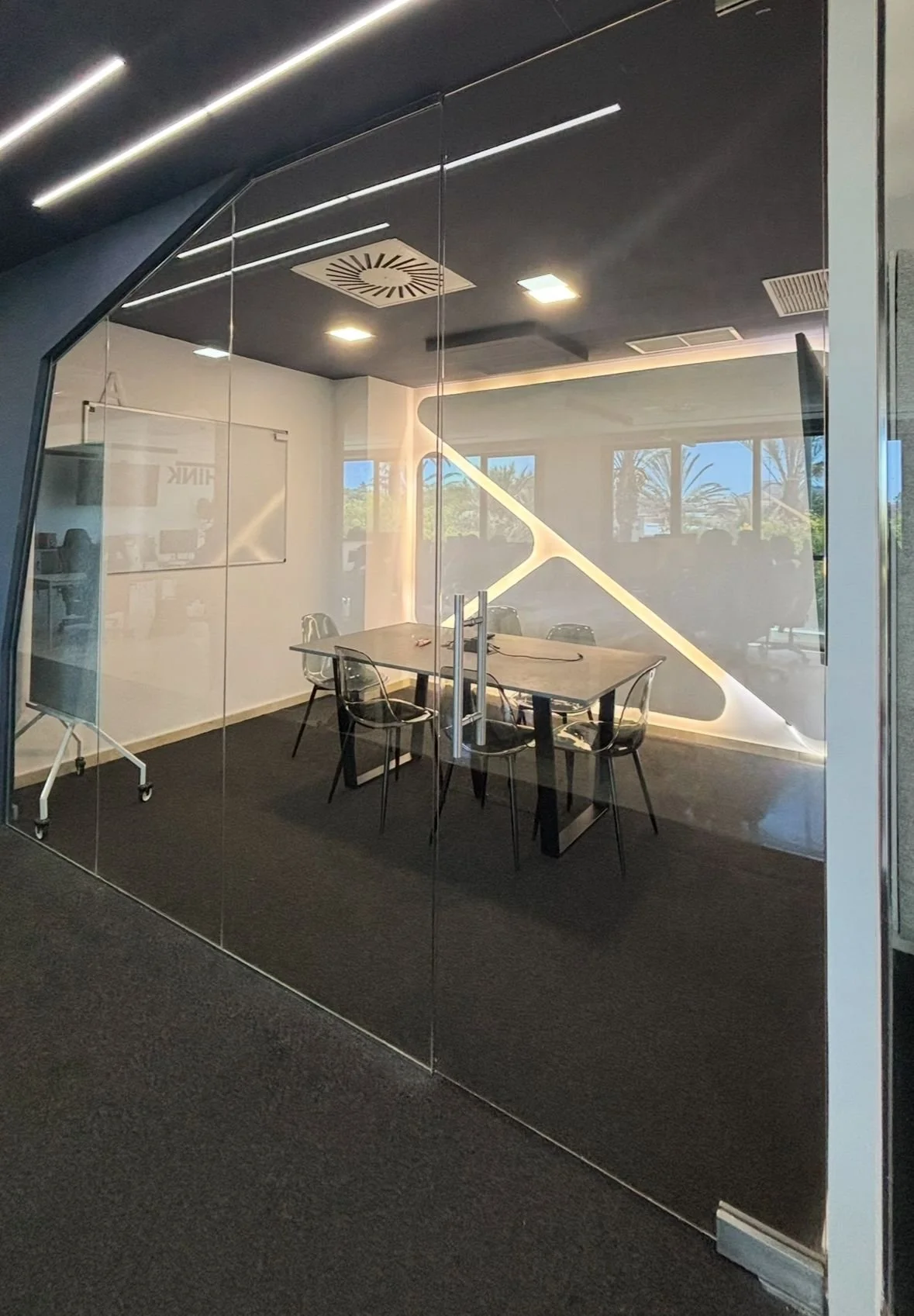 Sala de reuniones con mesa, sillas y paredes de vidrio en una oficina moderna