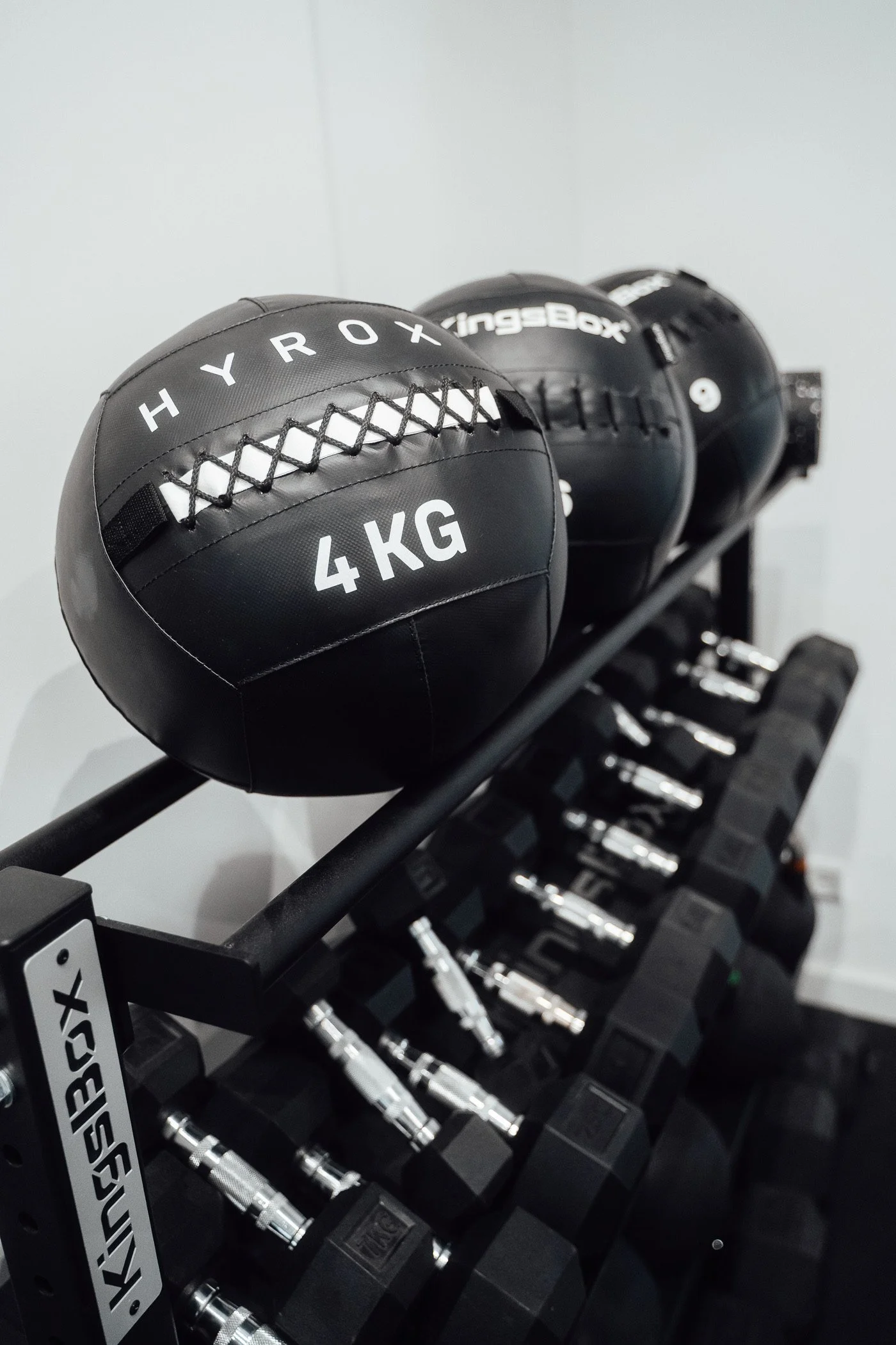 Schwarzer Medizinball mit 4 kg Gewicht, auf einer Hantelstange im Fitnessstudio.