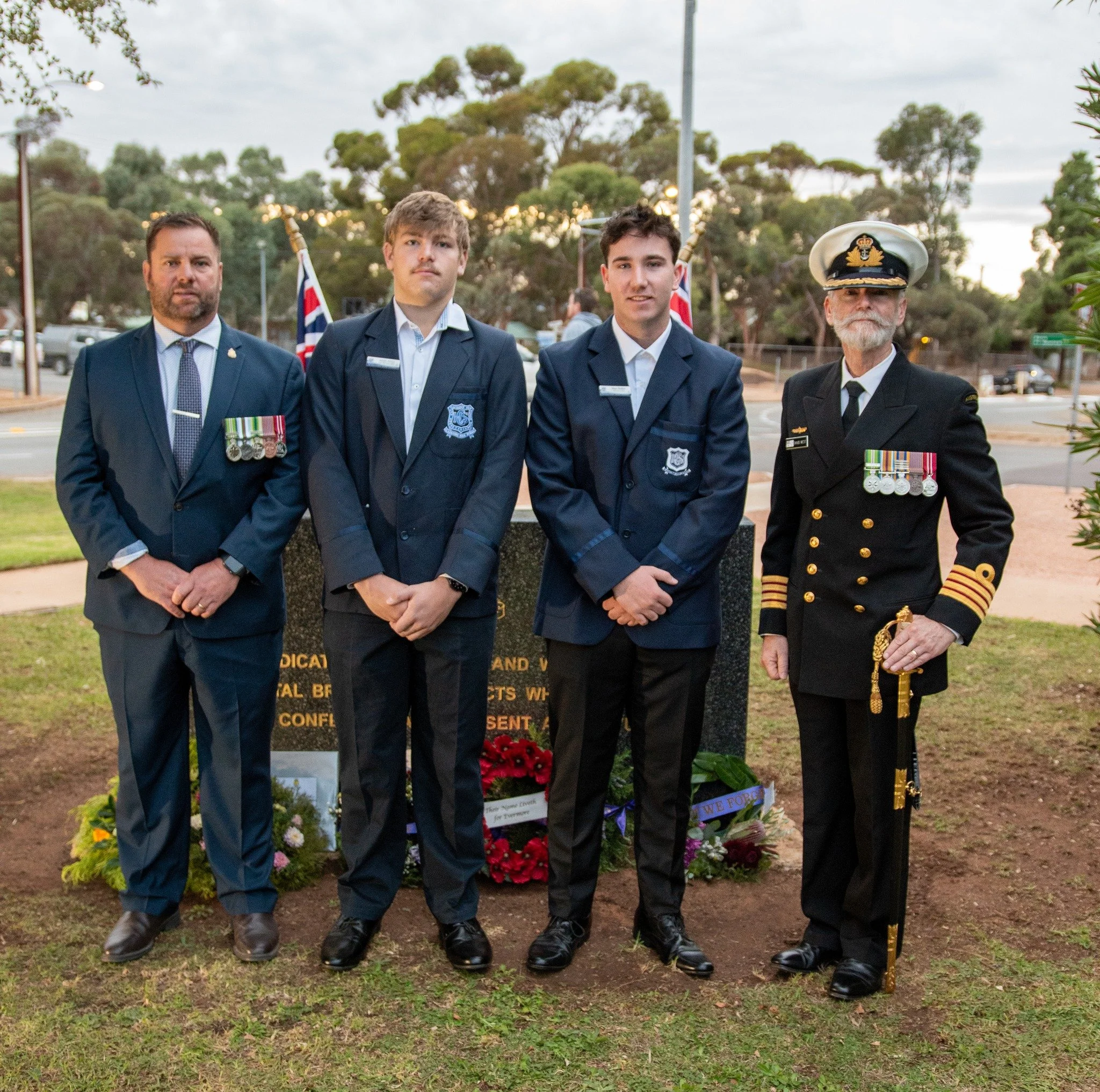 group of young and old soldiers smiling for a photo at an ANZAC ceremony 
