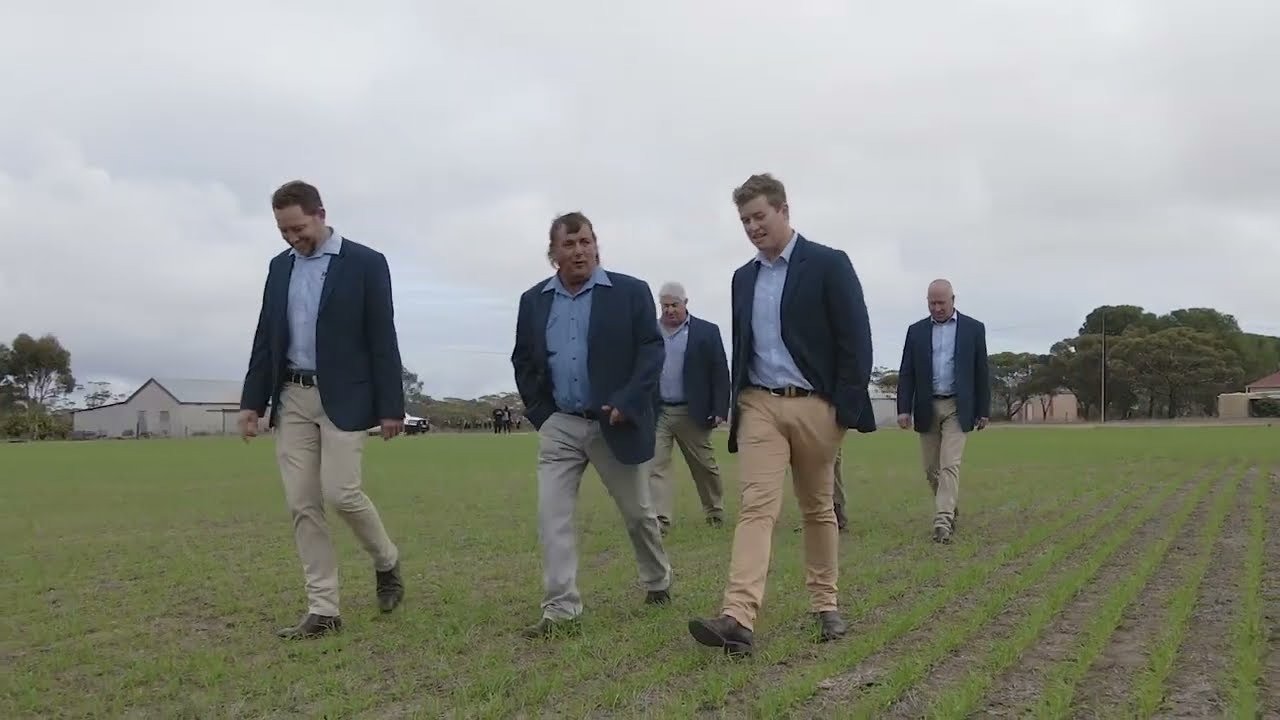 men in suits walking in a field for a photoshoot