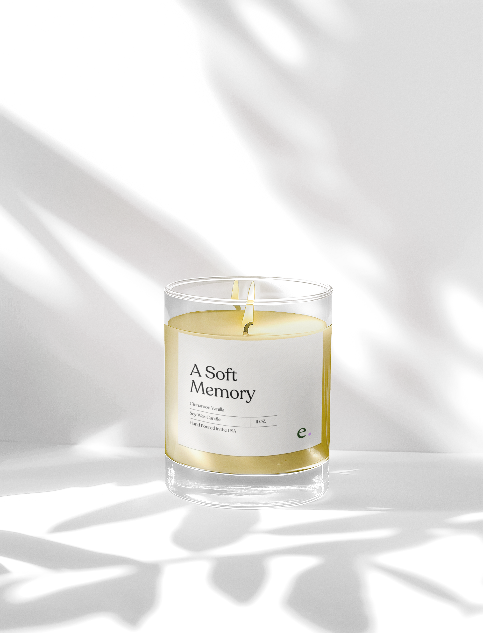Minimal frosted glass candle labeled “A Soft Memory” with white wax, styled on a bright white background with calm, natural light.