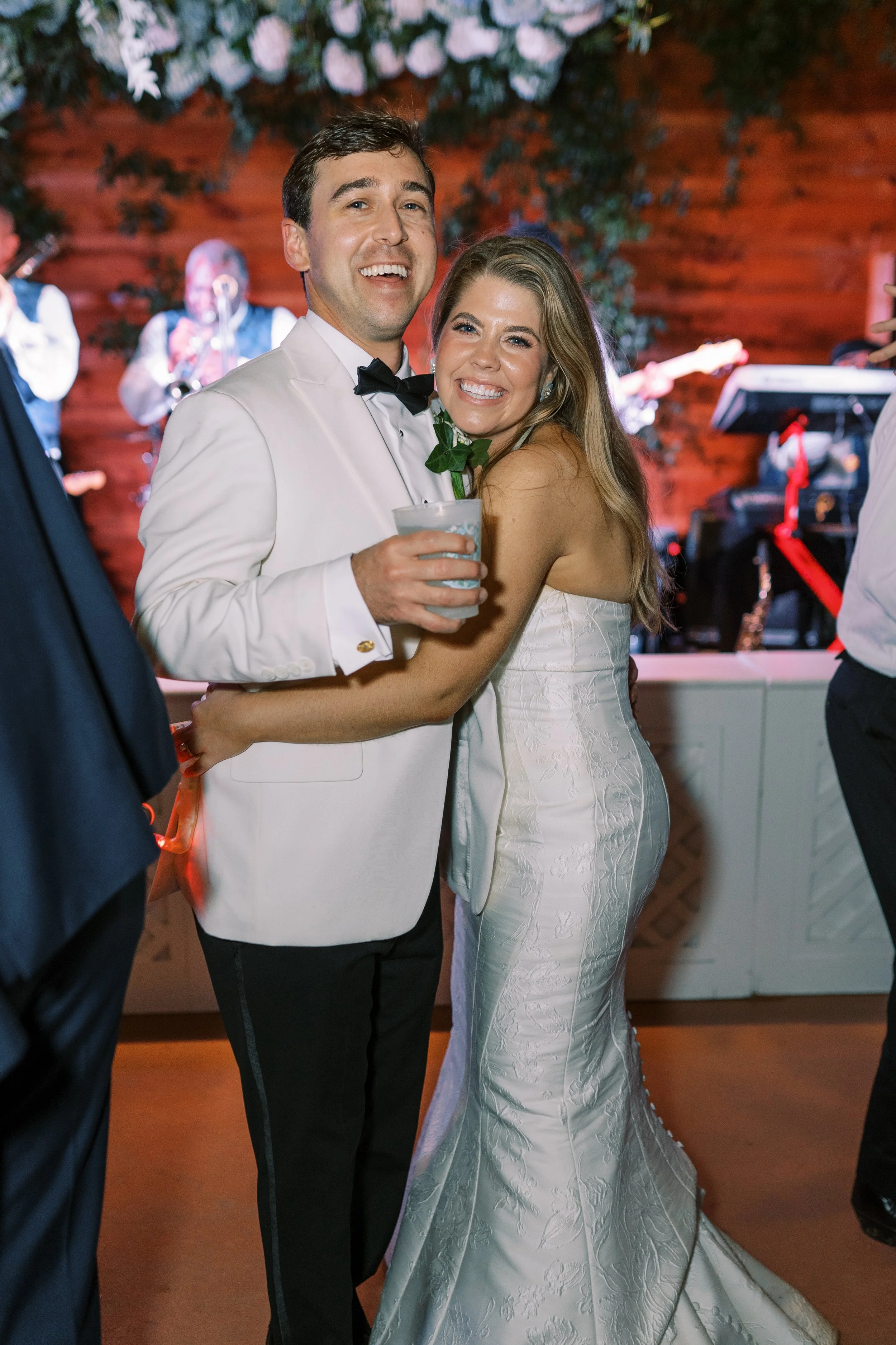 Groom smiling with bride on the dance floor with live band in the background