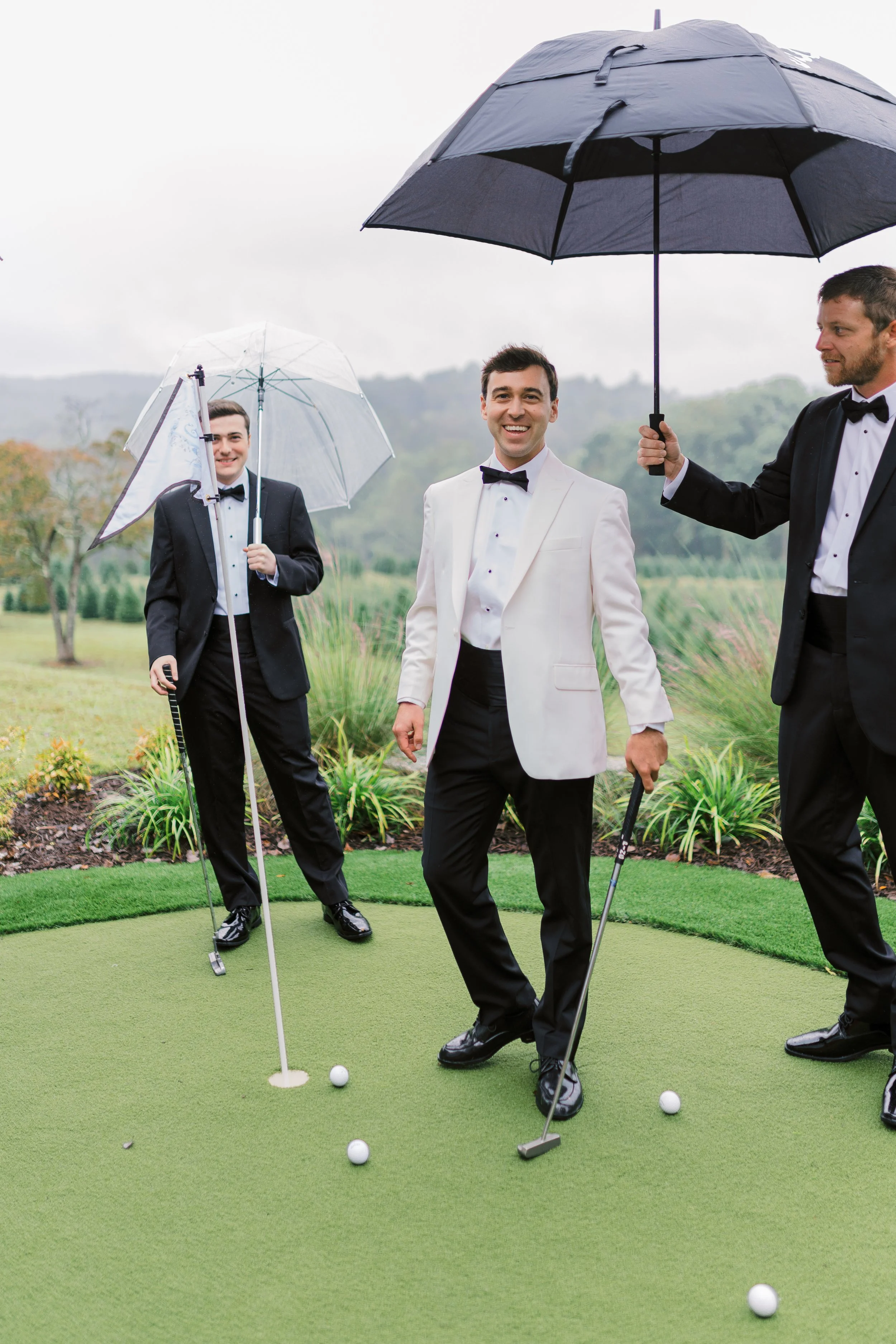 Groom and groomsmen laughing together under an umbrella