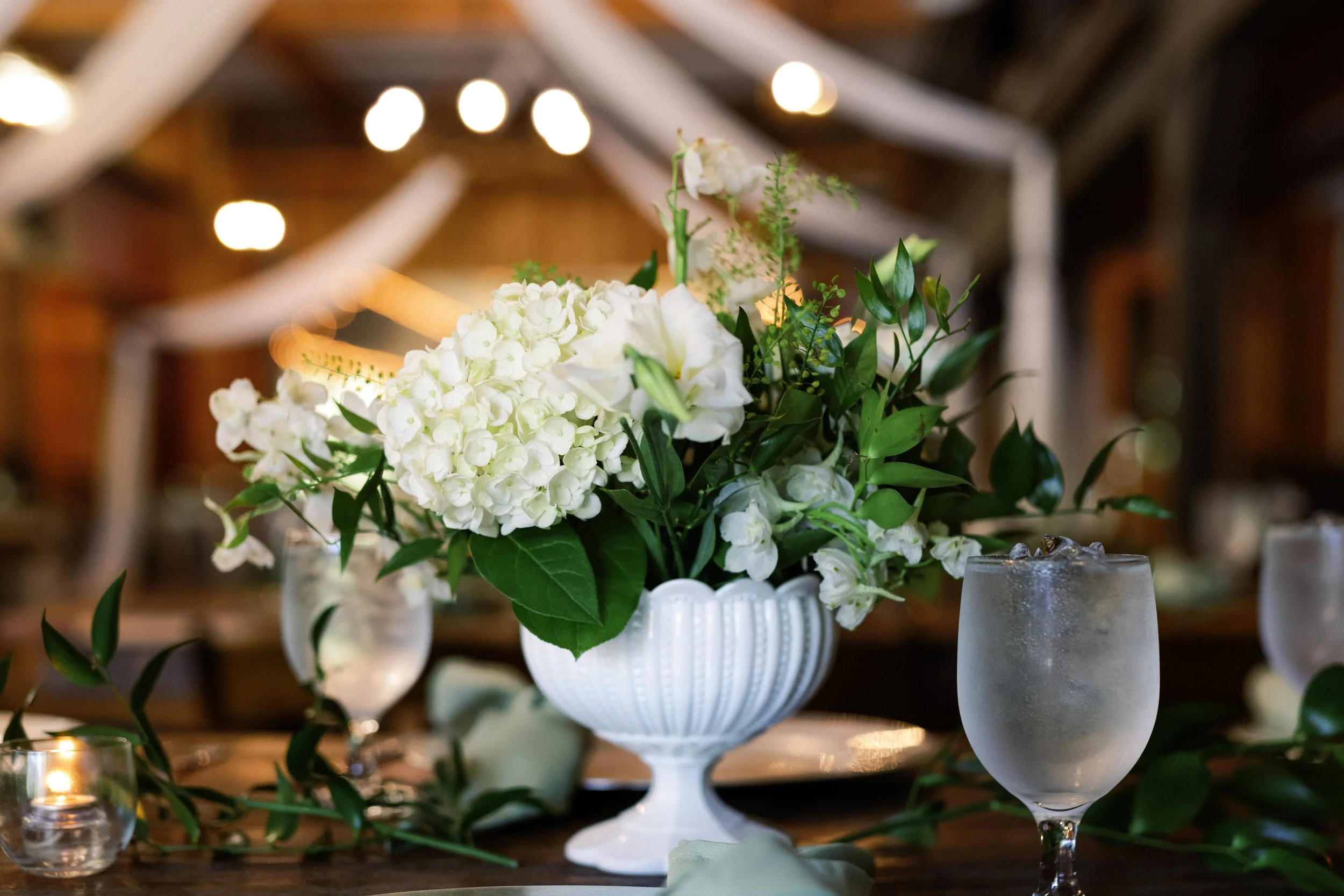 Reception centerpiece with white hydrangeas in a white urn on the dining table