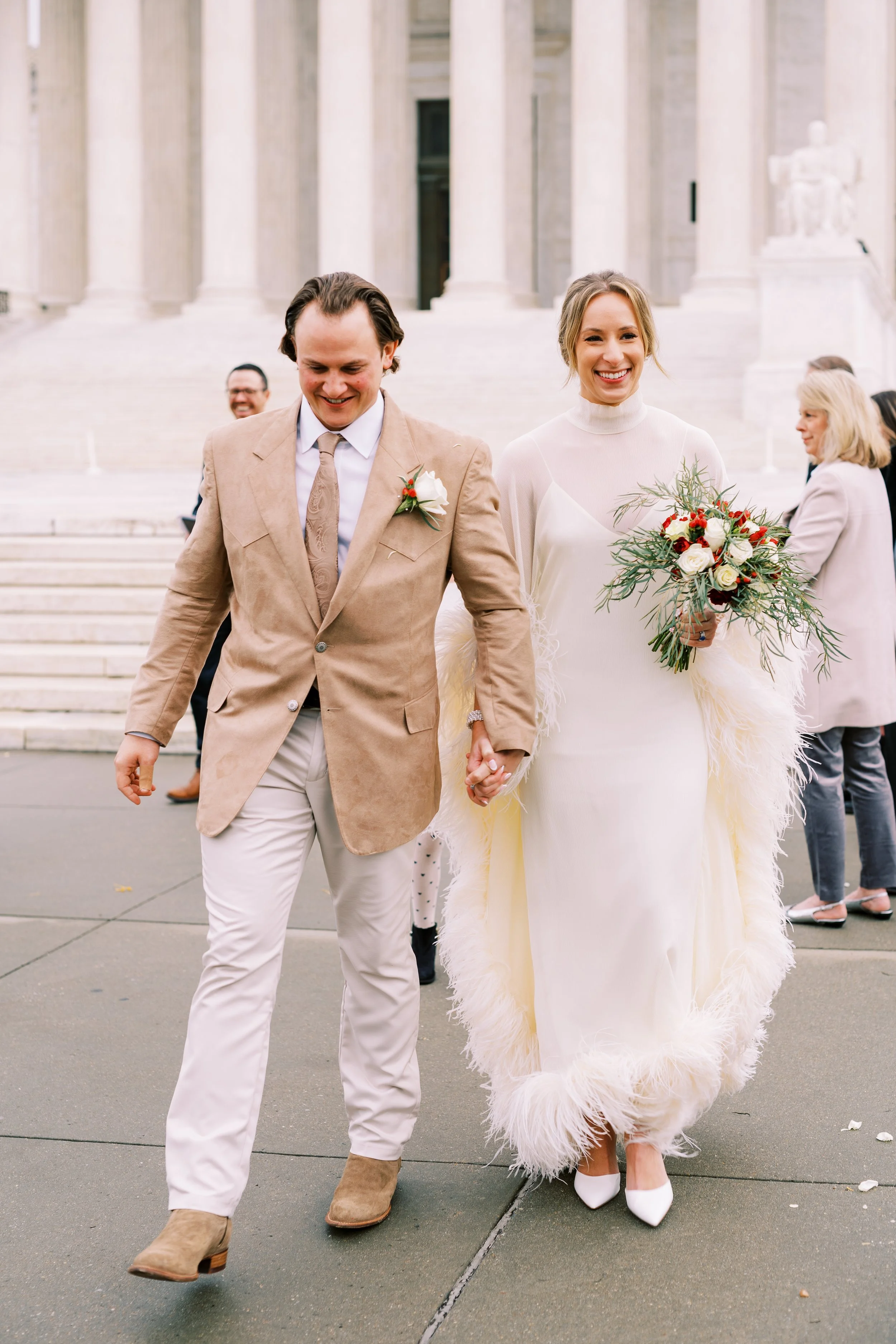 Bride and groom walking arm in arm across a plaza near a Washington DC monument