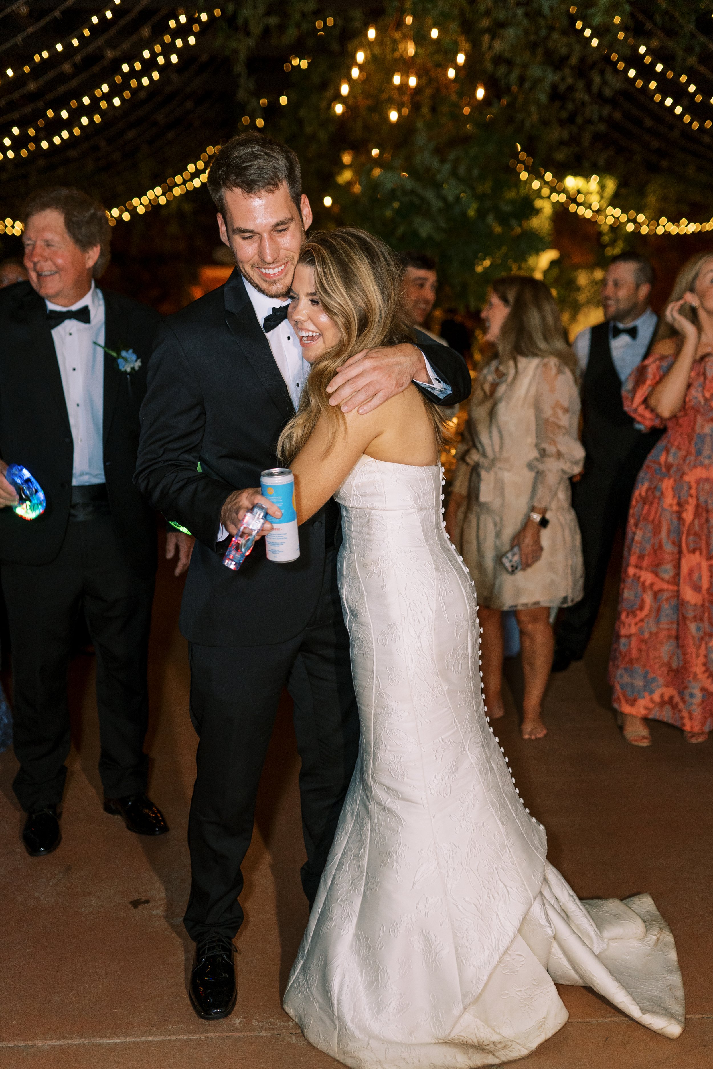 Bride and groom embracing surrounded by dancing guests