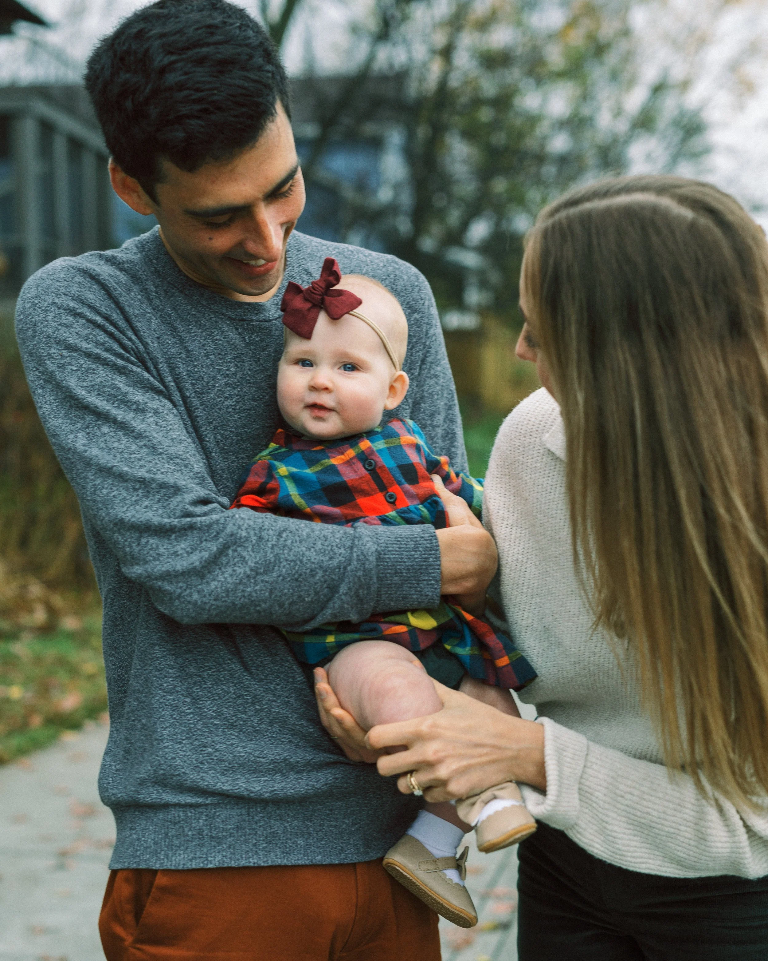 Parents kissing on the Atlanta BeltLine path while holding their baby girl, Atlanta, Georgia
