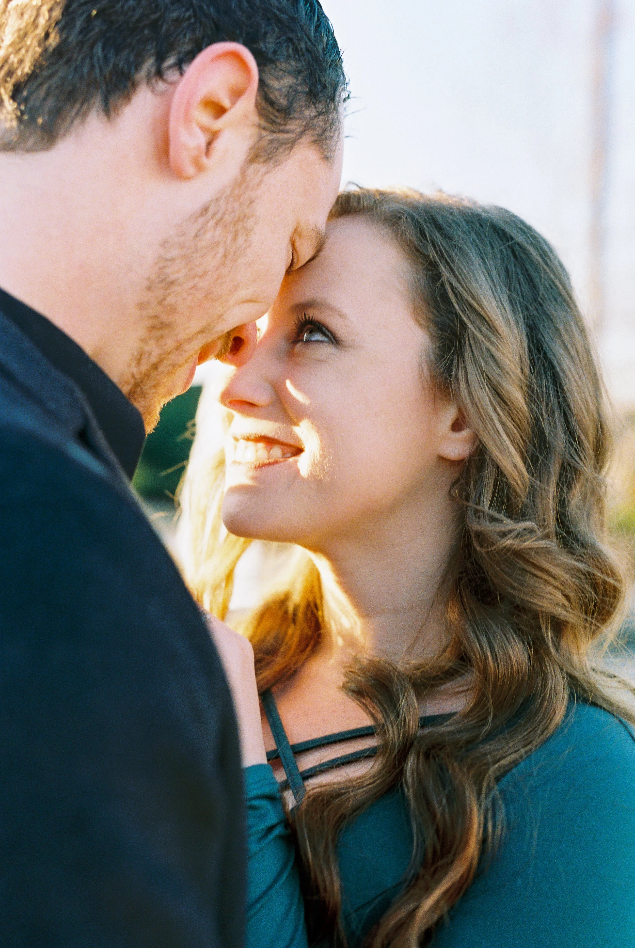 Maddie smiles up at Conner with sunlit hair during their engagement session in Dallas, Georgia.