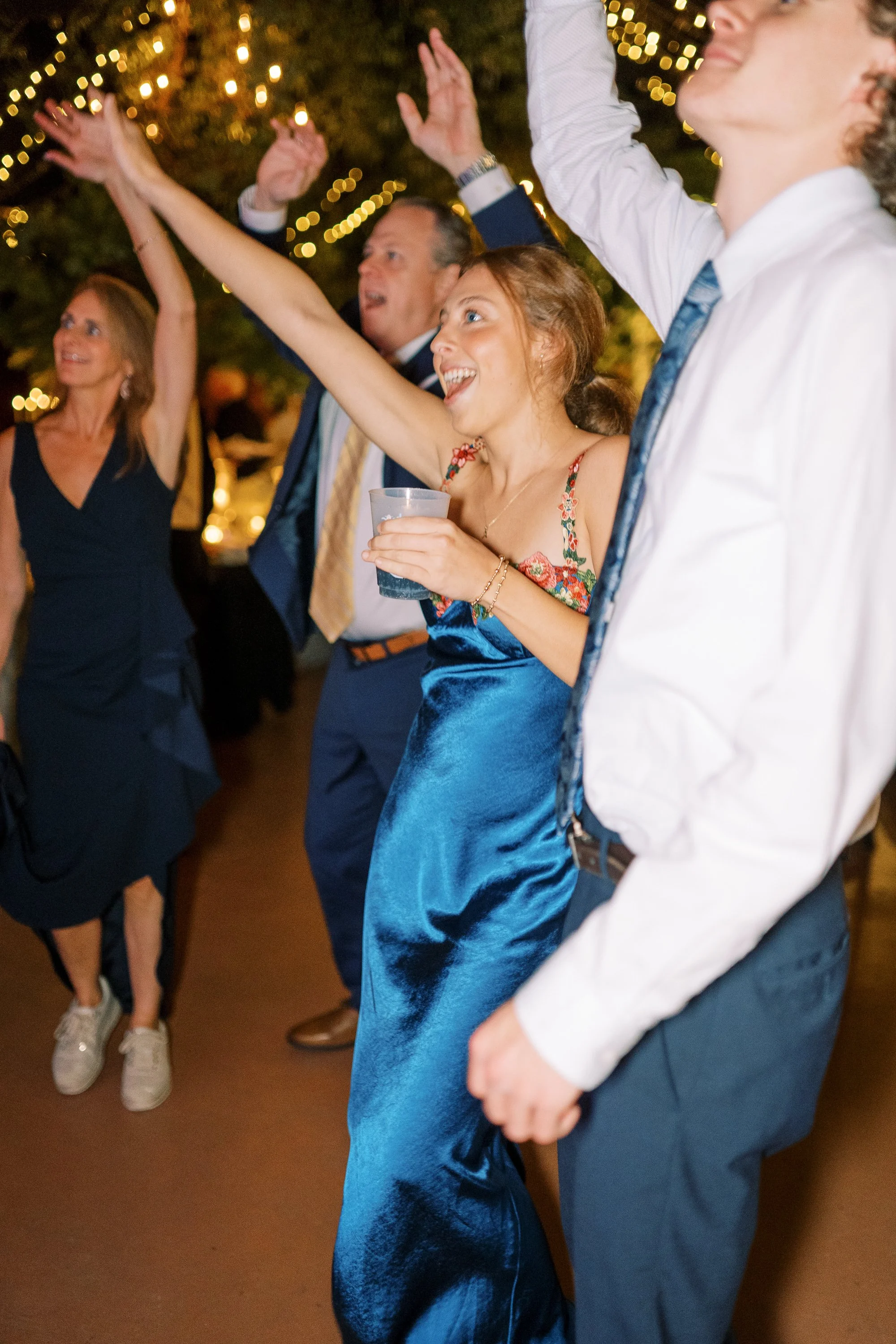 Guests dancing with arms raised in celebration on the dance floor