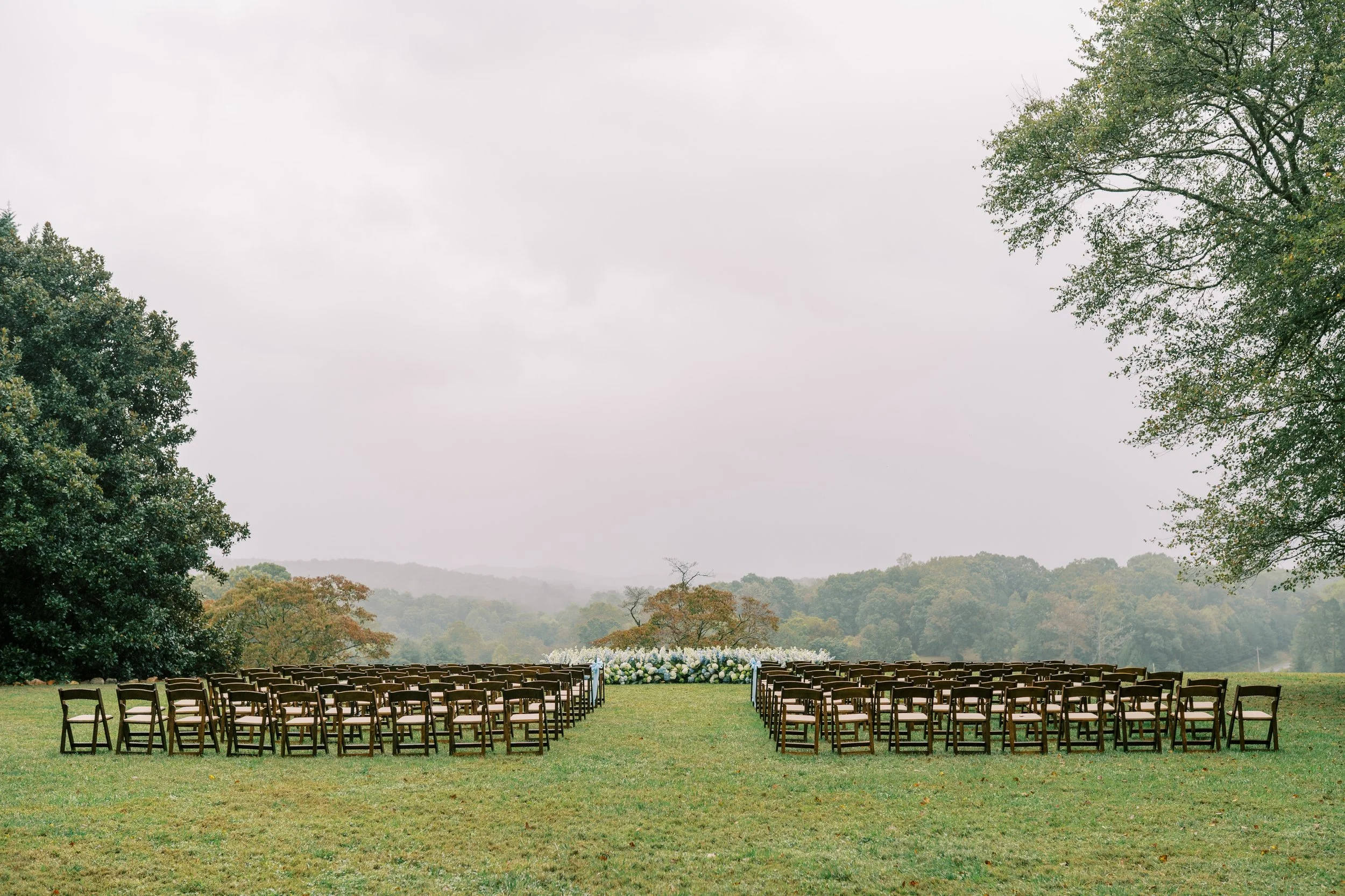 Wide view of the ceremony seating rows set in a misty field