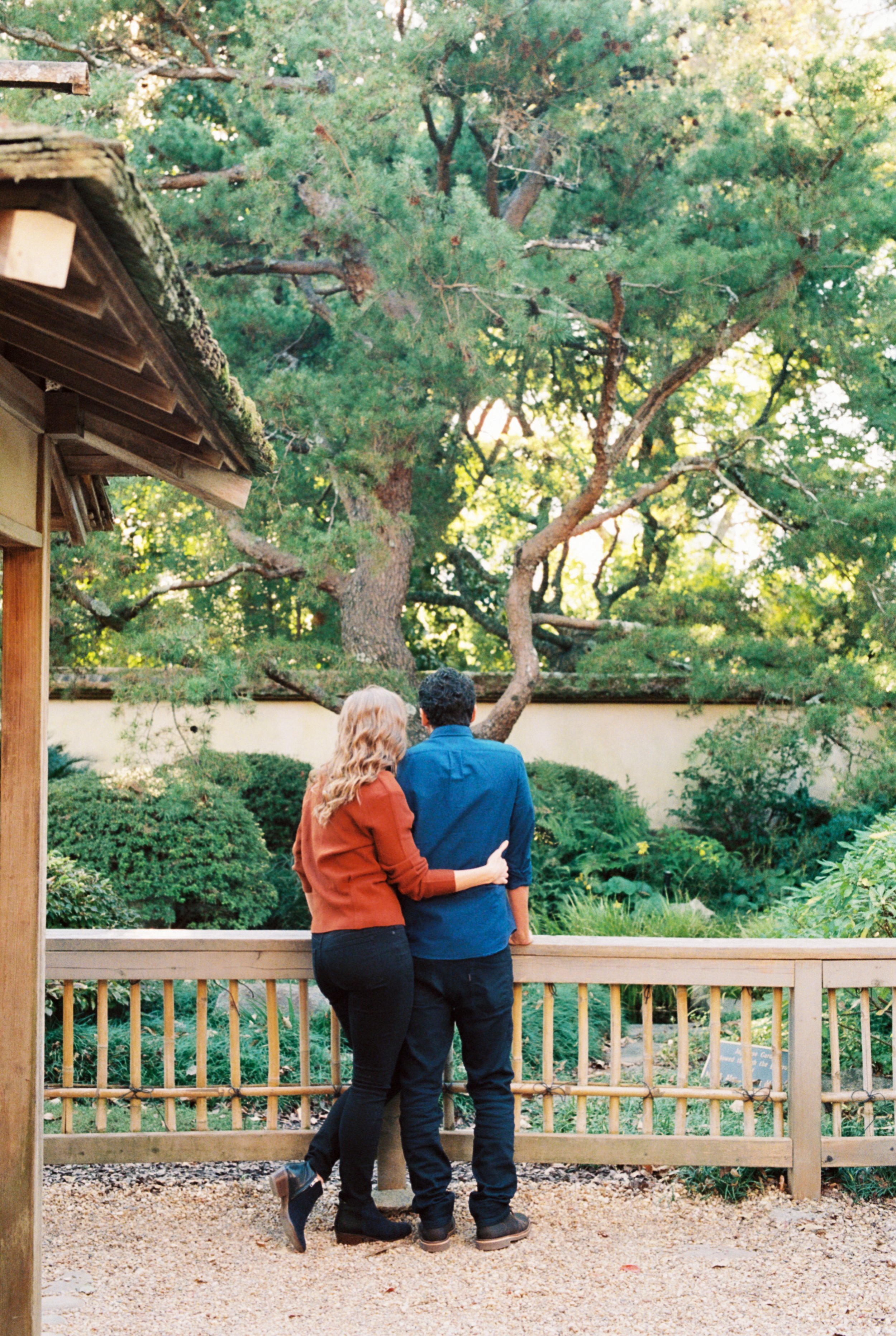 Couple standing arm in arm at a wooden railing, gazing out over the lake at Atlanta Botanical Garden