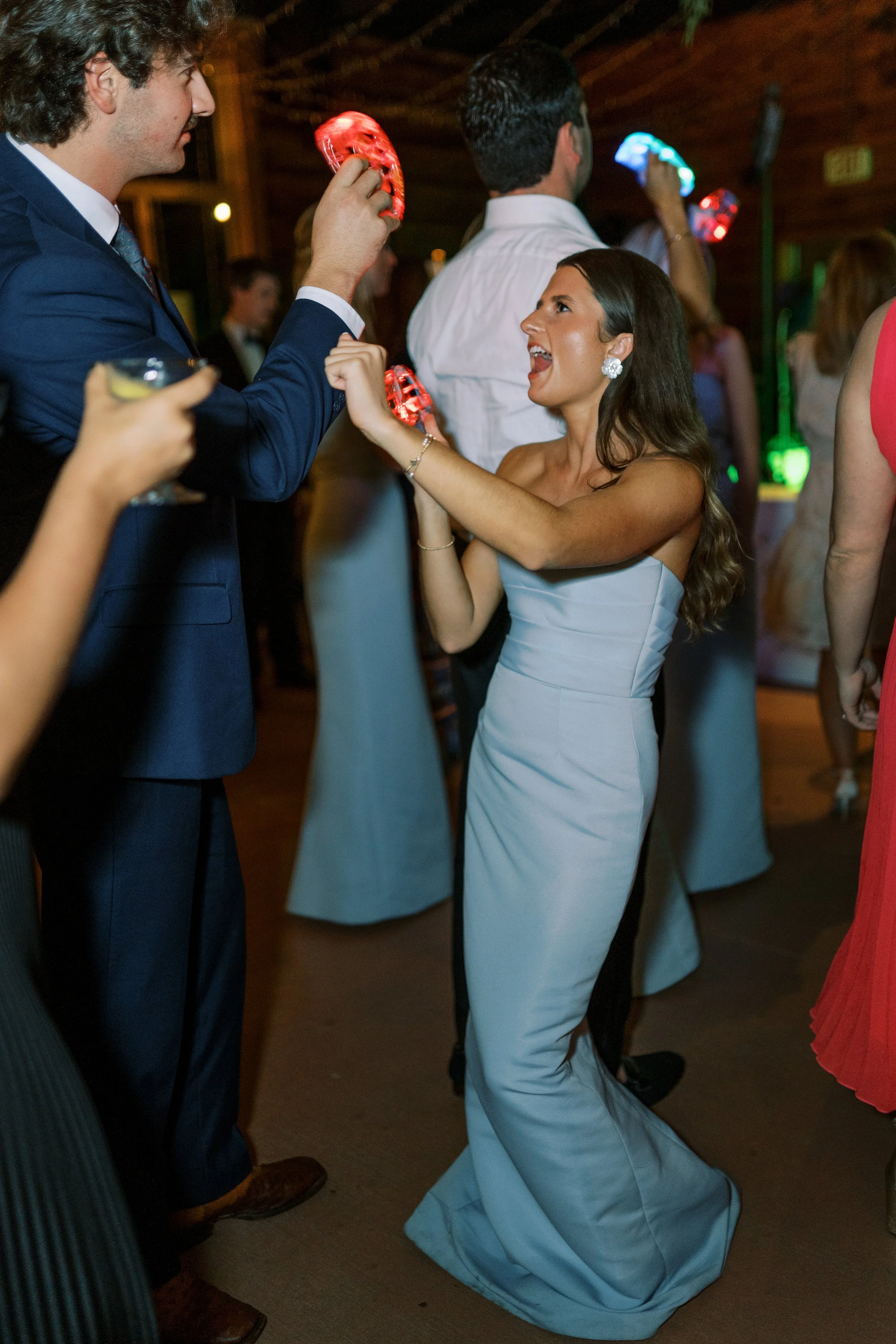 Guests dancing on the reception dance floor with colorful lighting