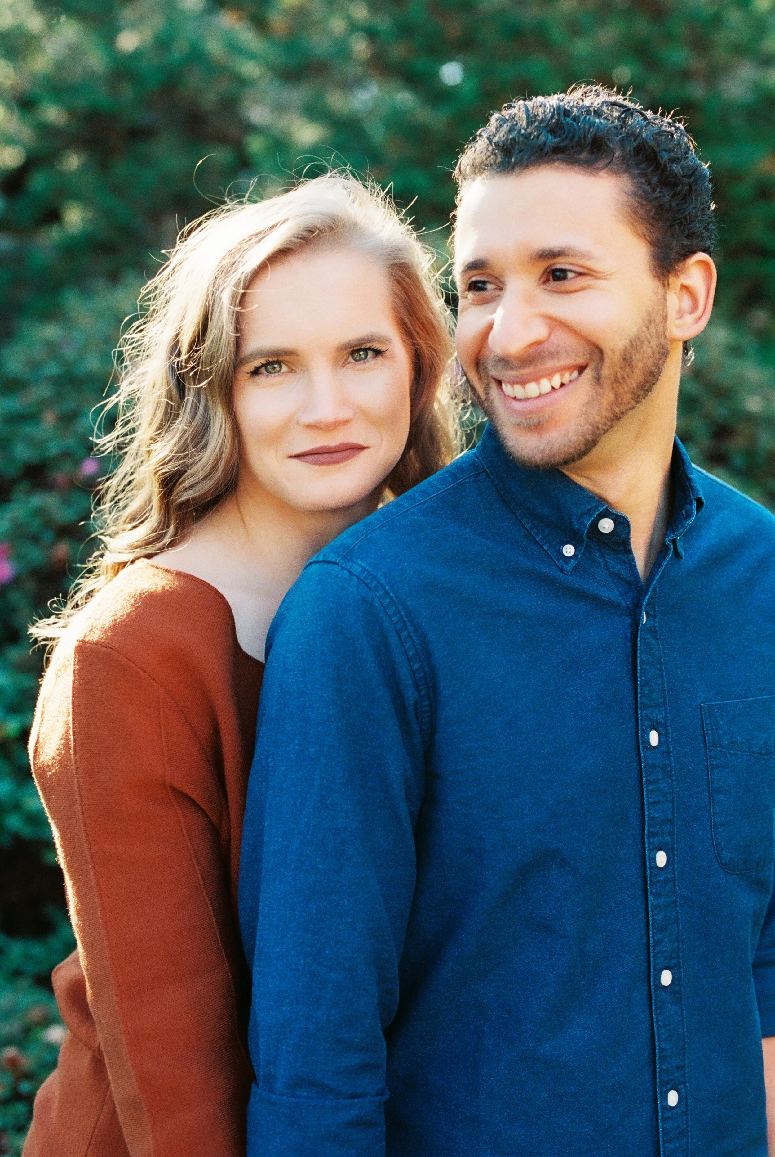 Close-up portrait of the engaged couple smiling cheek to cheek outdoors