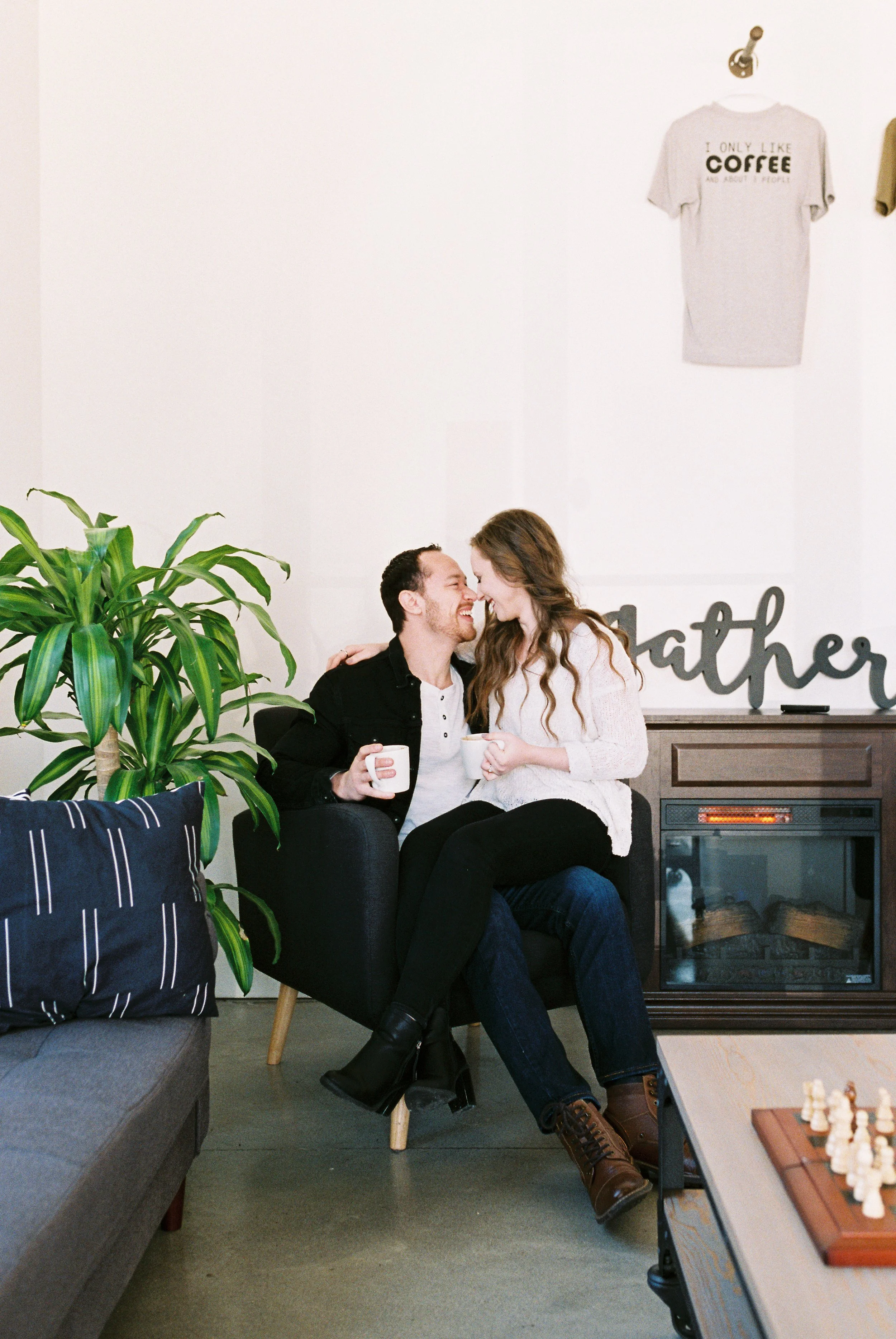 Conner and Maddie kiss while sharing an armchair by the fireplace in a Dallas, Georgia coffee shop.