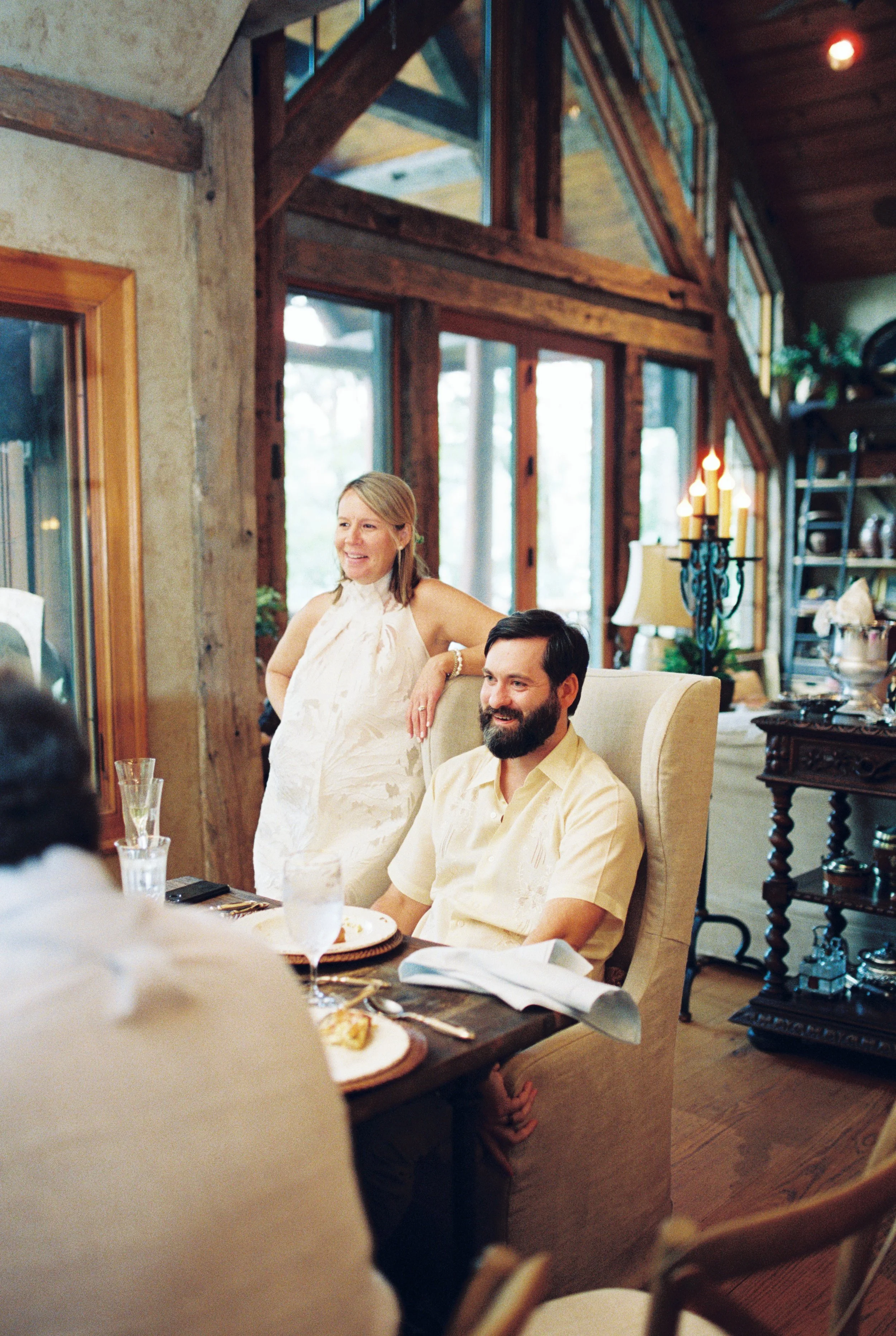 Bride and groom sharing a candid moment seated together indoors near large windows