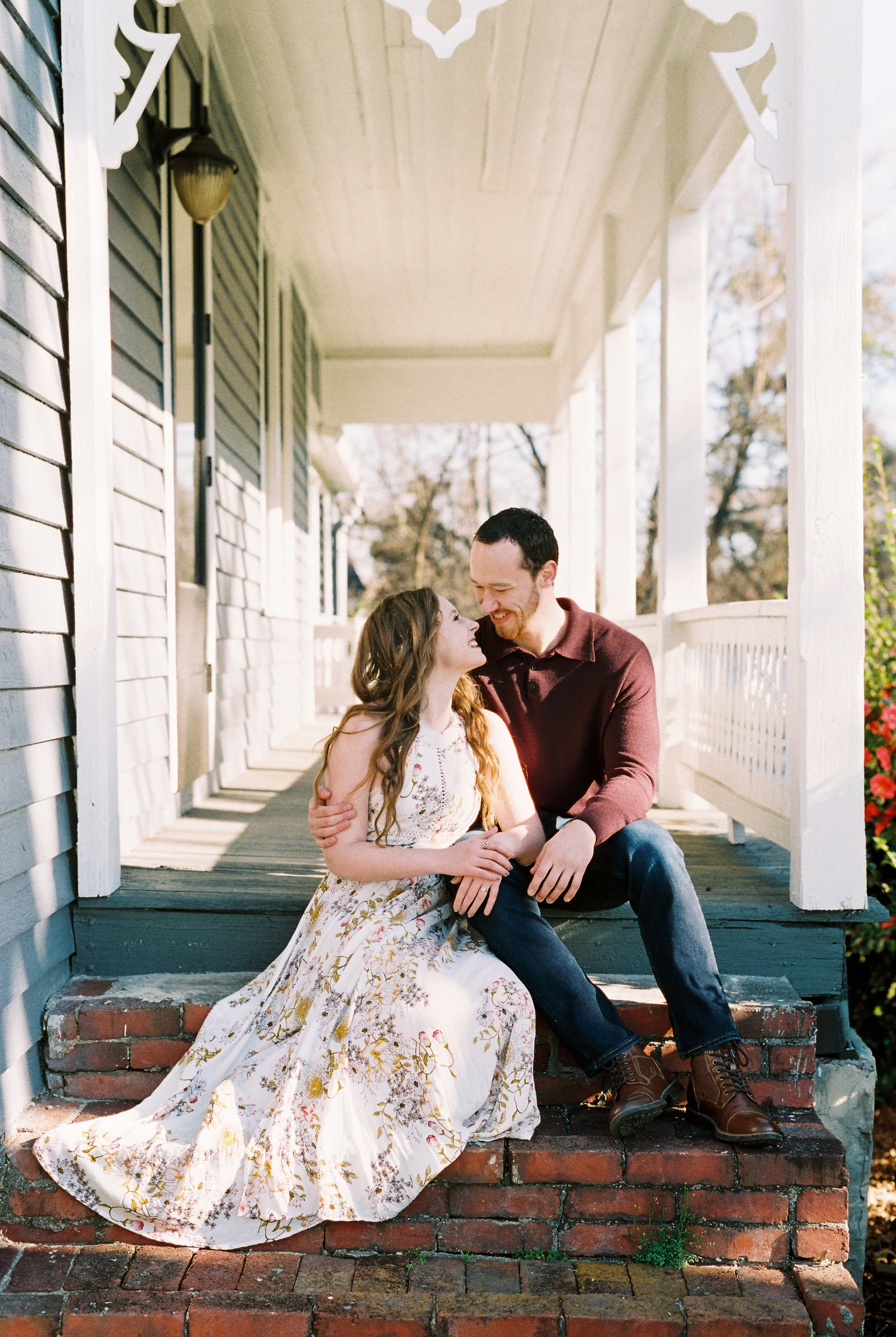 Conner and Maddie lean in close together while seated on the porch steps of a historic home in Dallas, Georgia.