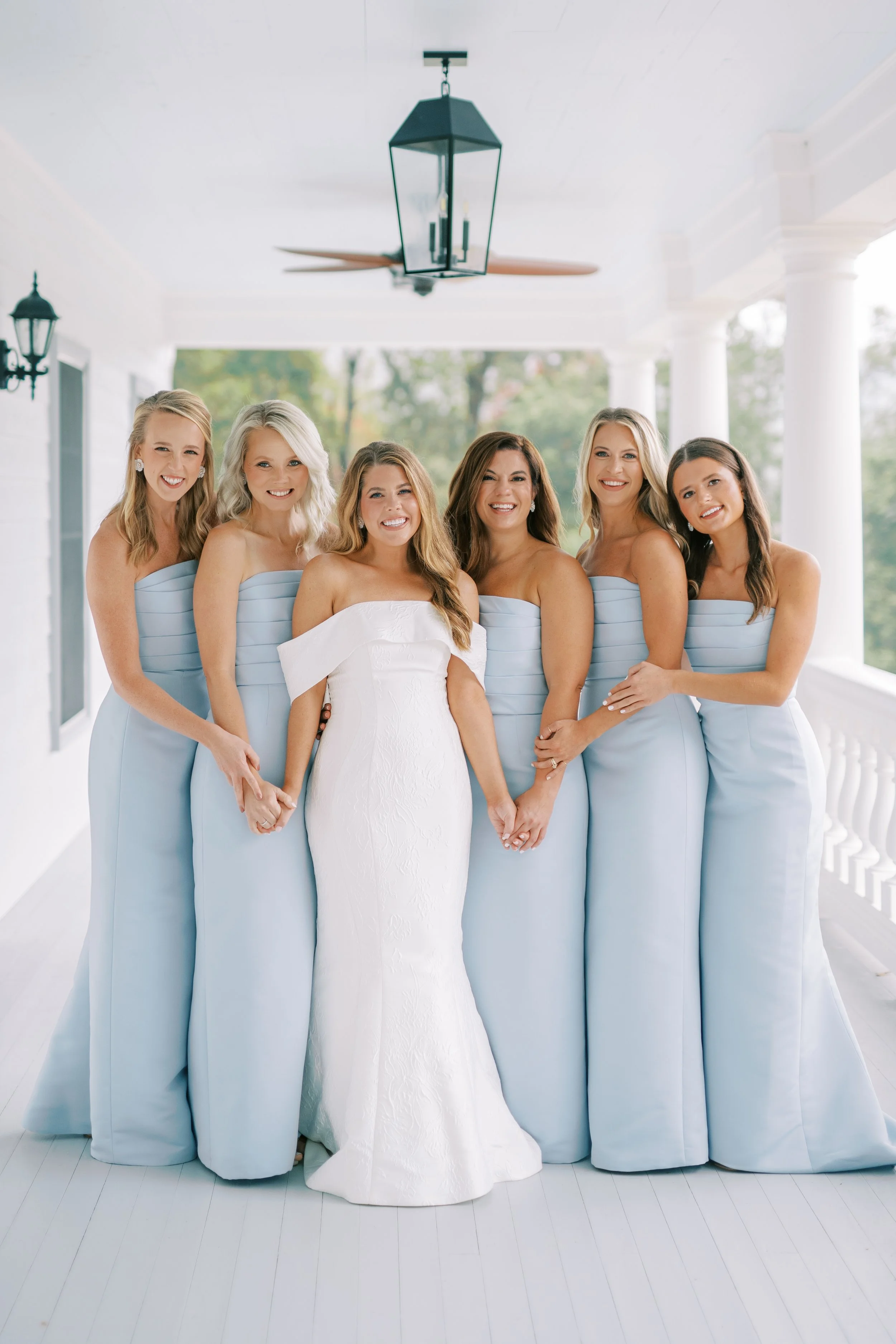 Bride with full bridesmaid party group portrait on the porch