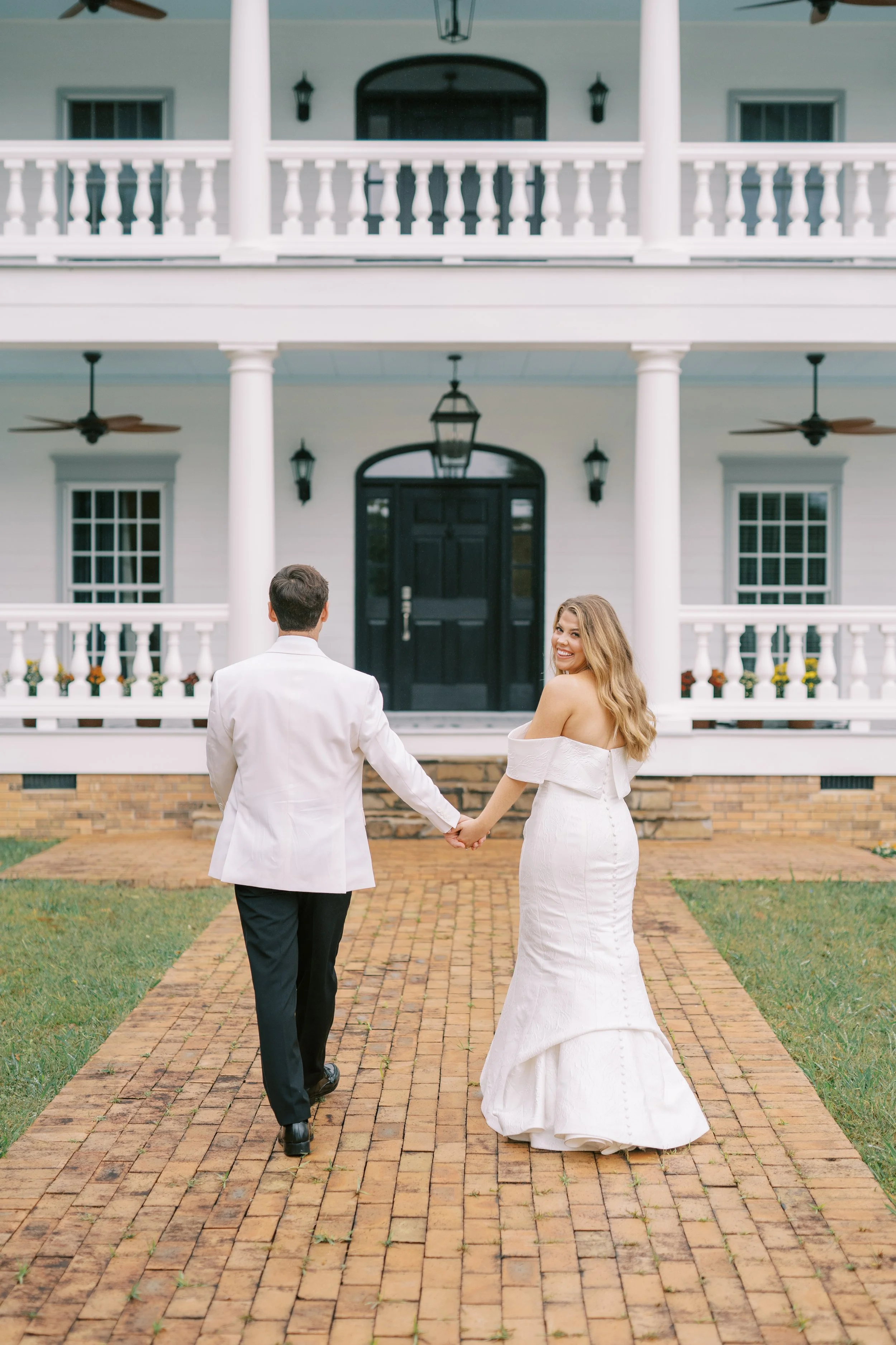 Newlyweds embracing on the front lawn of the plantation house