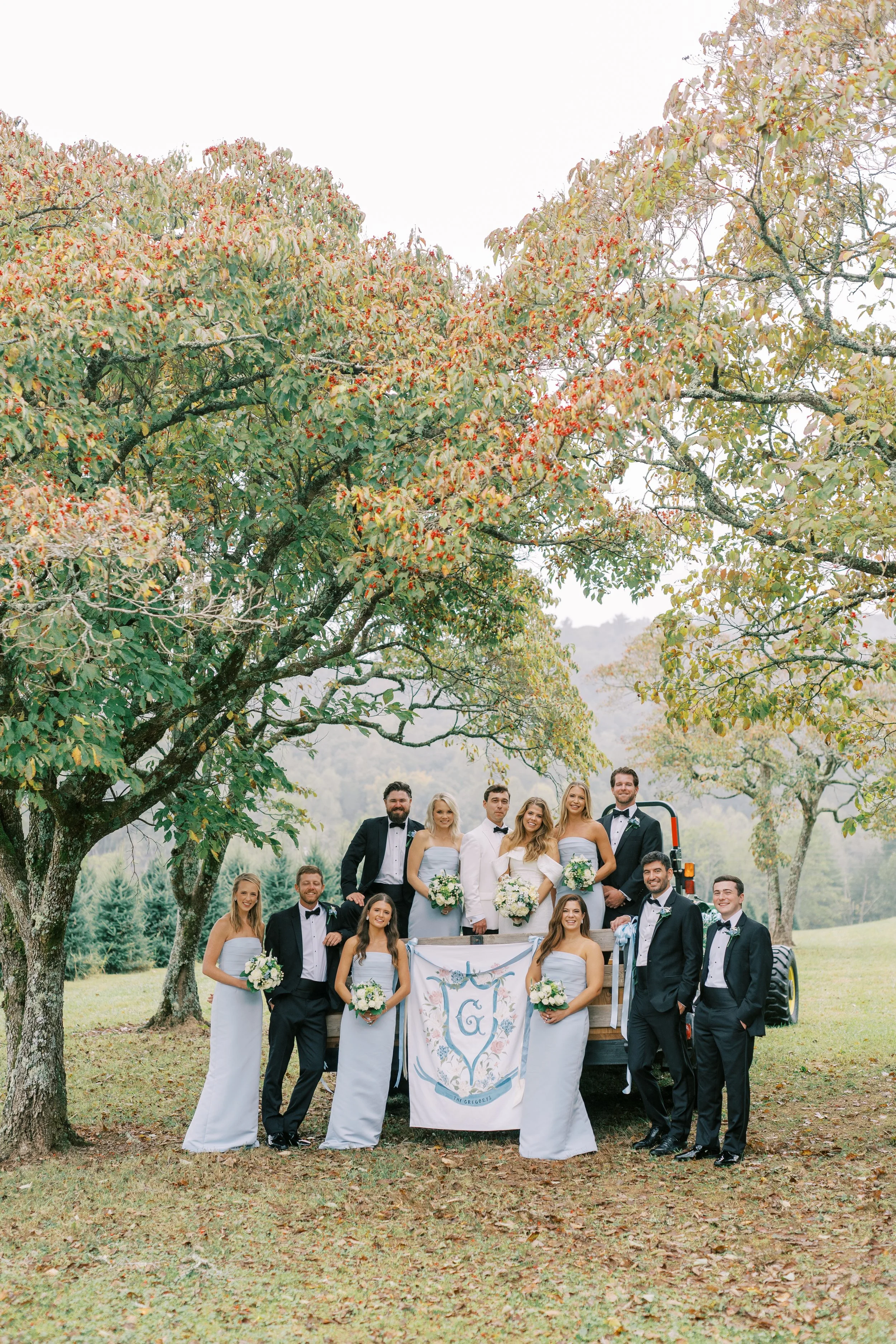 Wedding party group portrait under a large autumn tree