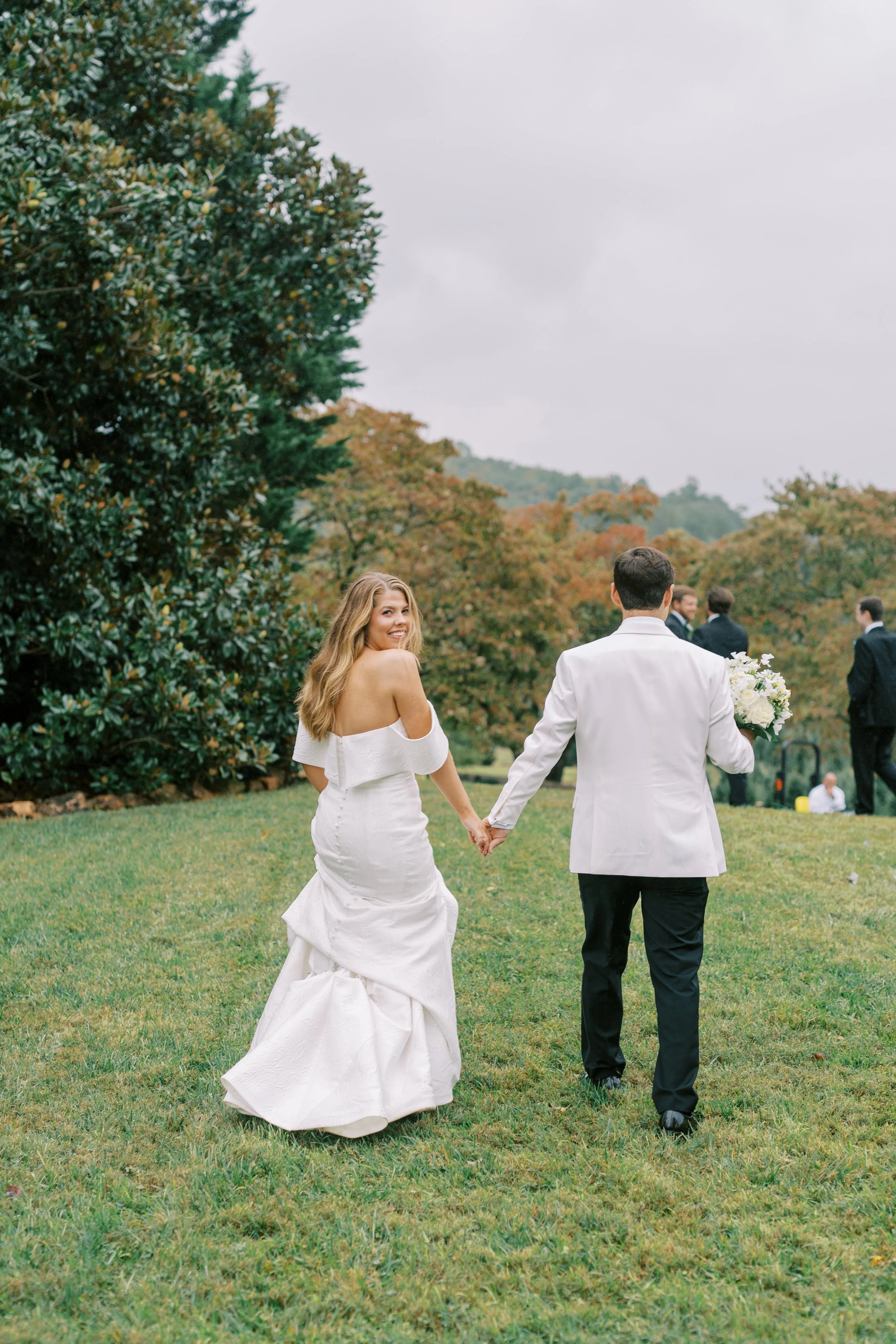 Couple walking hand in hand across the open lawn with mountain views