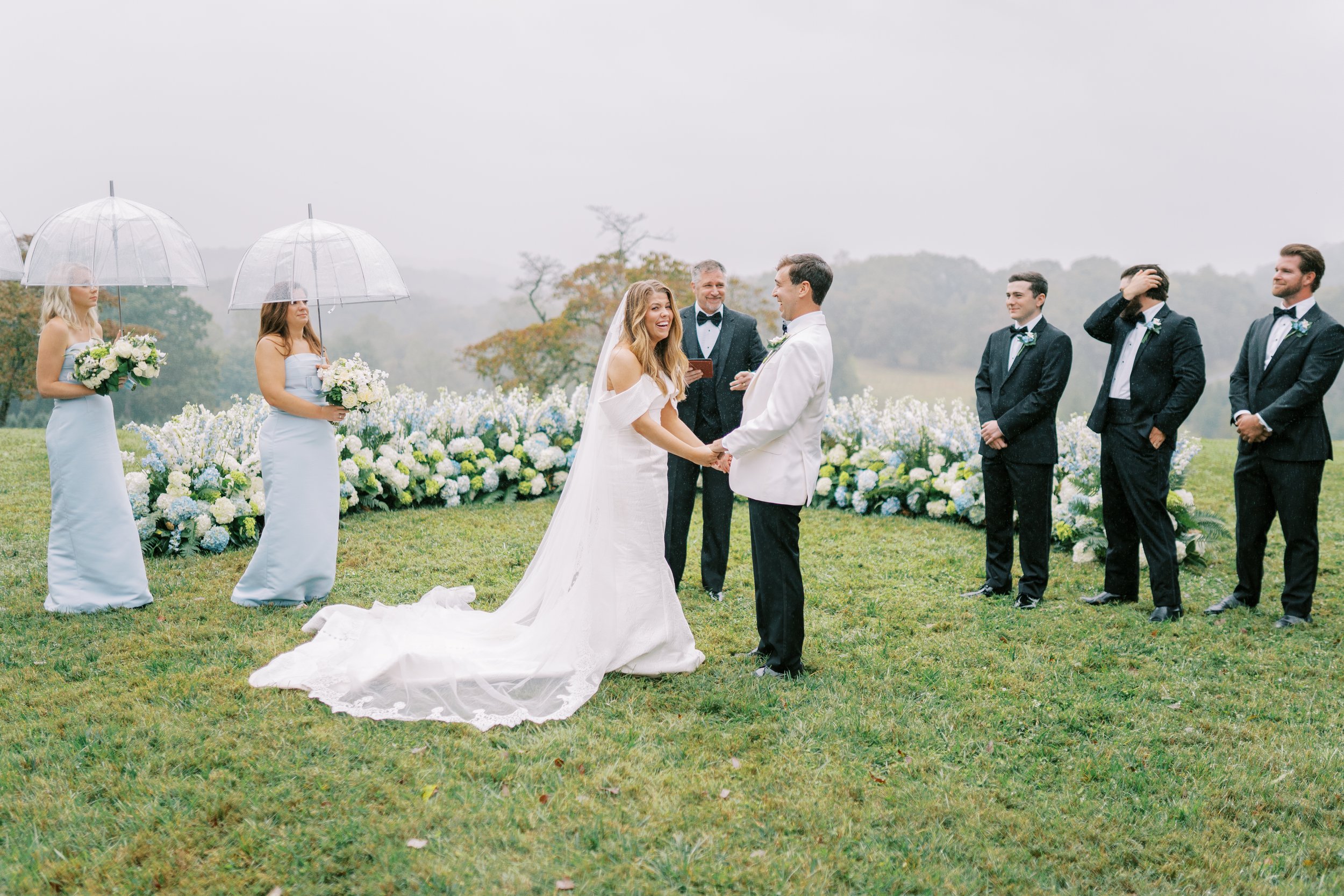 Couple exchanging vows with the officiant and wedding party in the rain