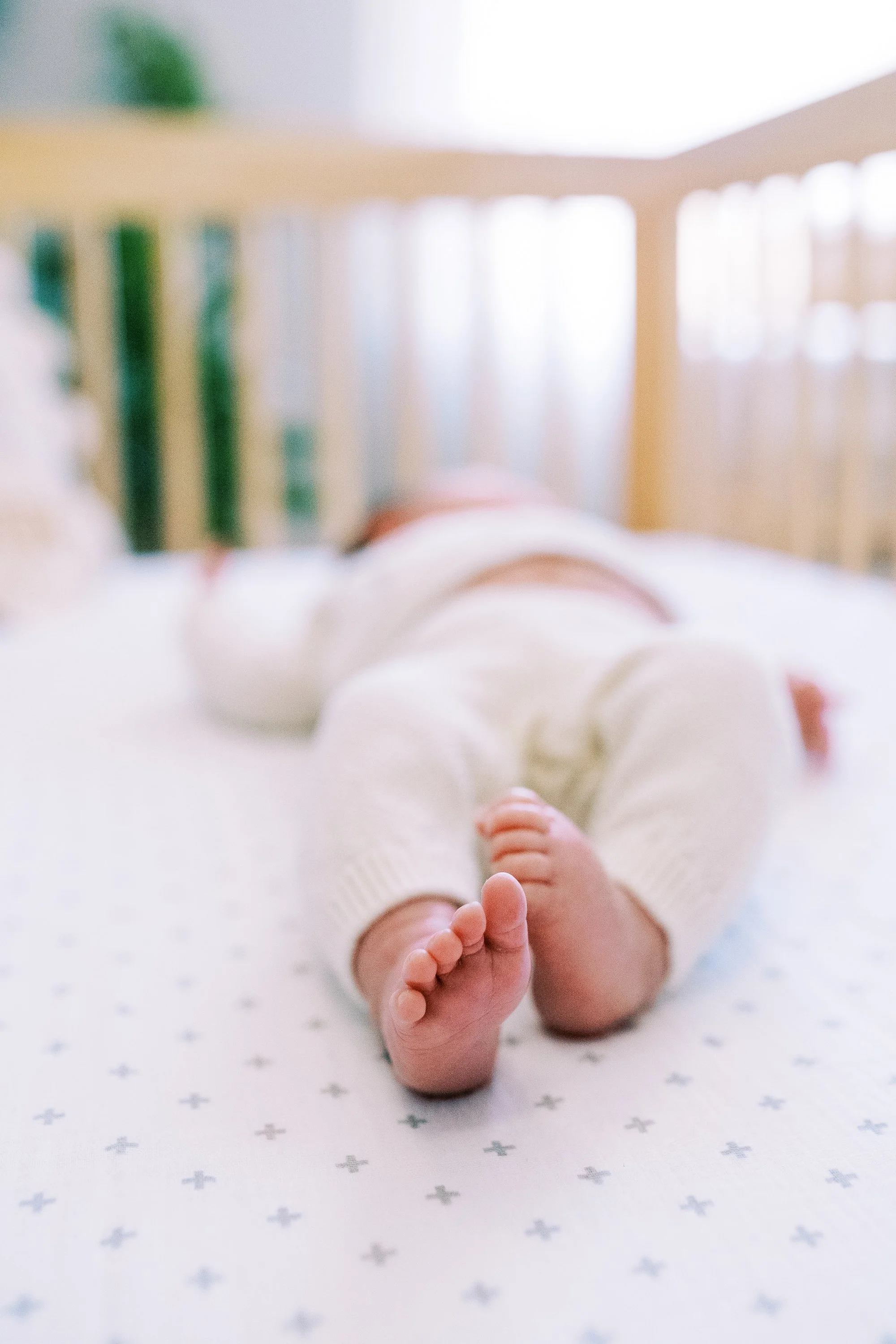 Newborn baby's tiny feet in focus while lying in the crib, Roswell, Georgia