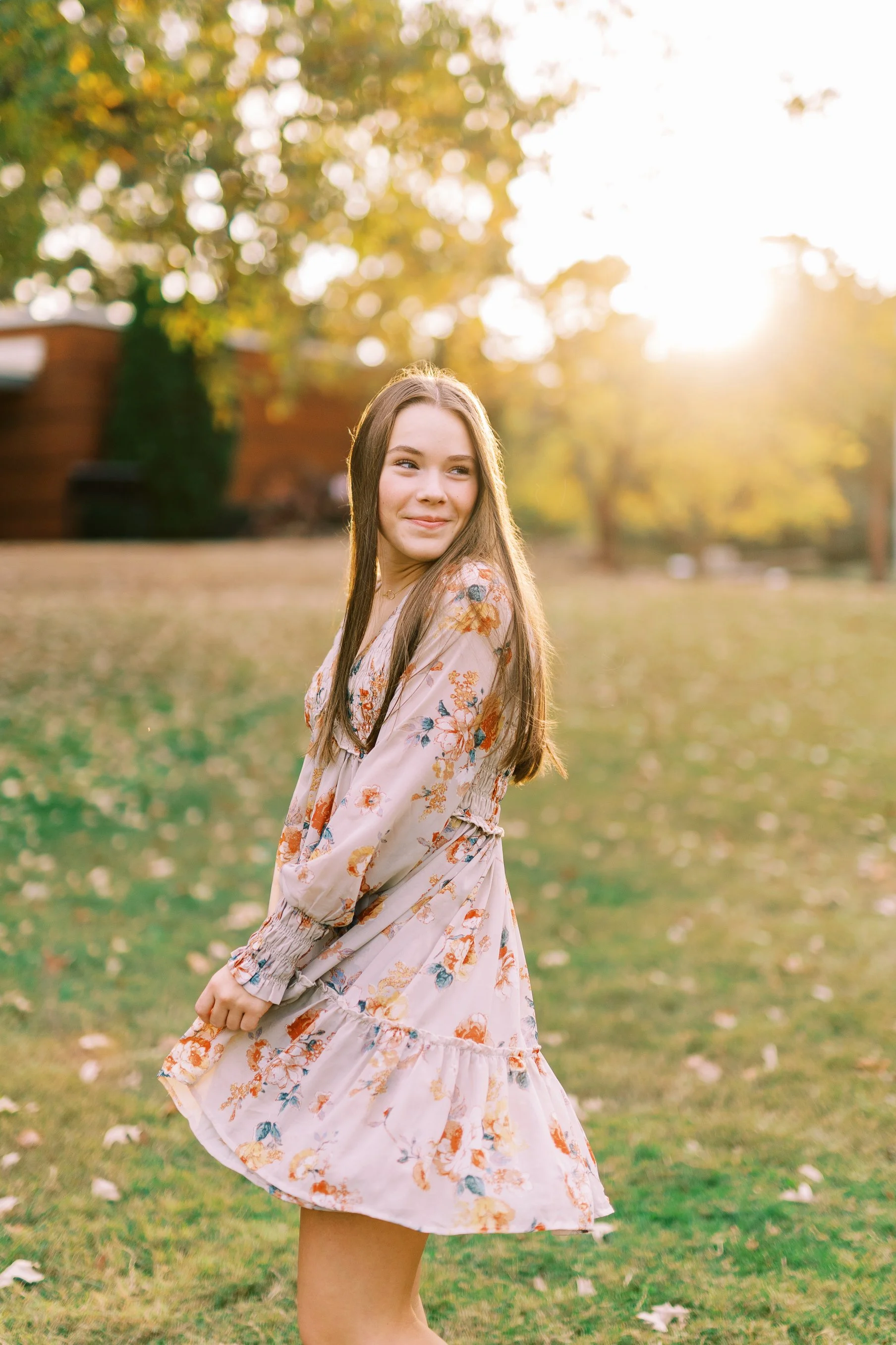 Senior portrait of Hannah twirling in a floral dress in a sunlit meadow at Kennesaw Mountain Battlefield Park in Kennesaw, Georgia