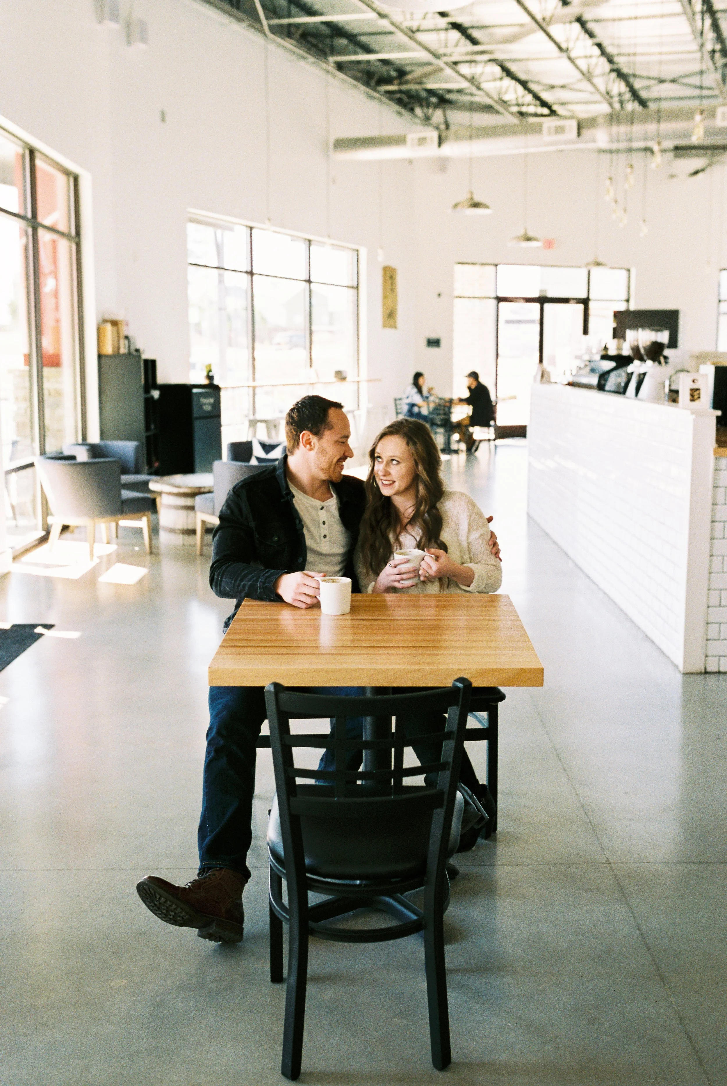 A wide view of Conner and Maddie seated at a table inside the Dallas, Georgia coffee shop.