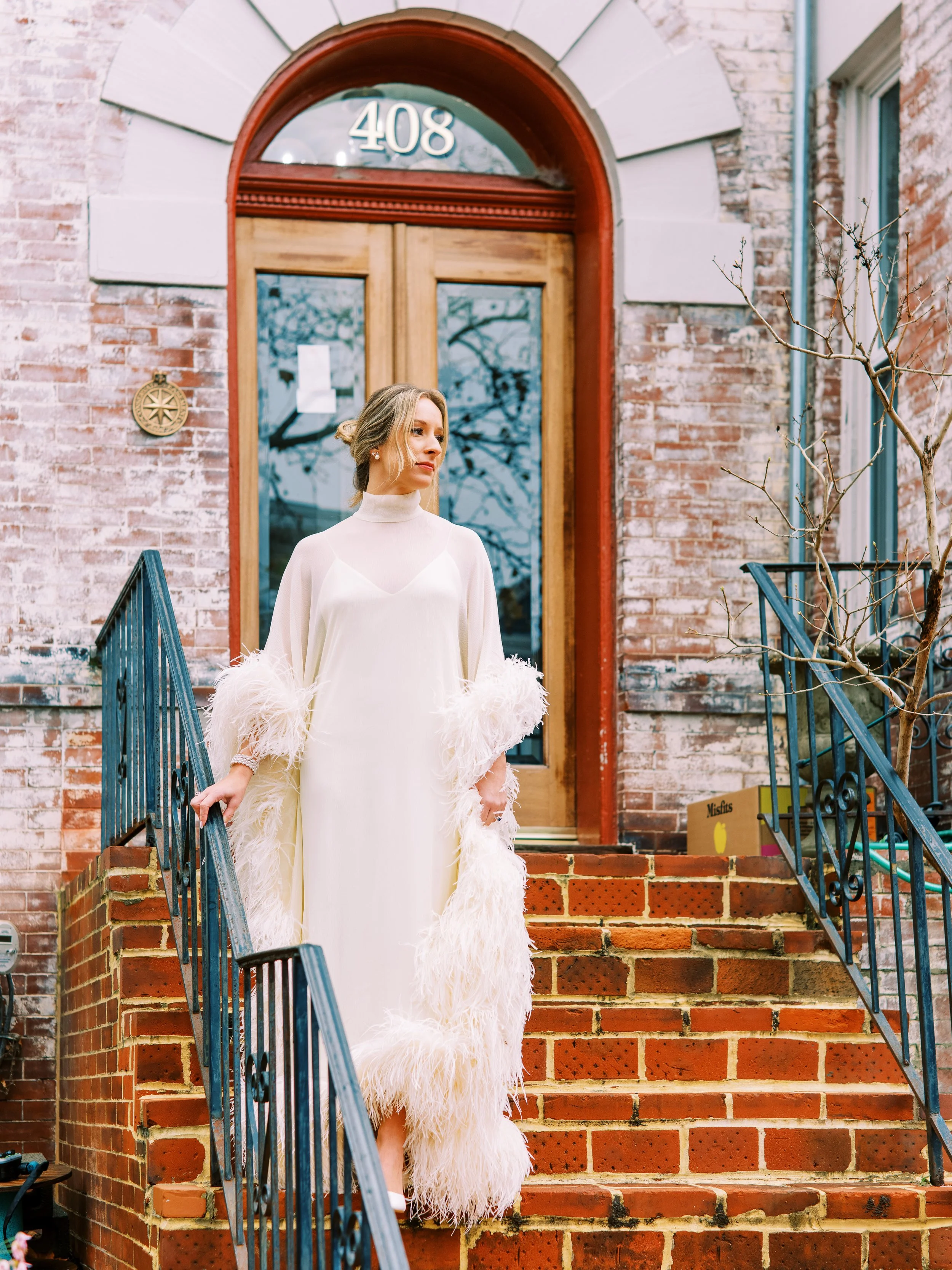 Bride standing solo on the front steps of a historic brick building