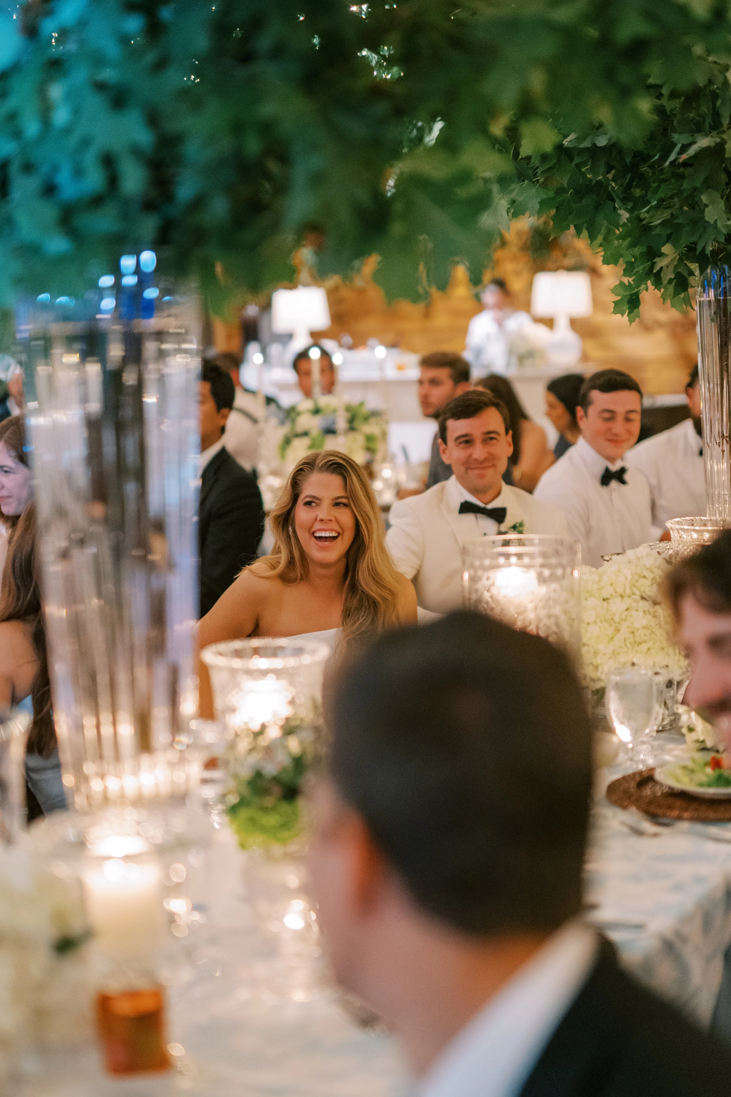 Bride laughing with groomsmen at the head table during reception toasts