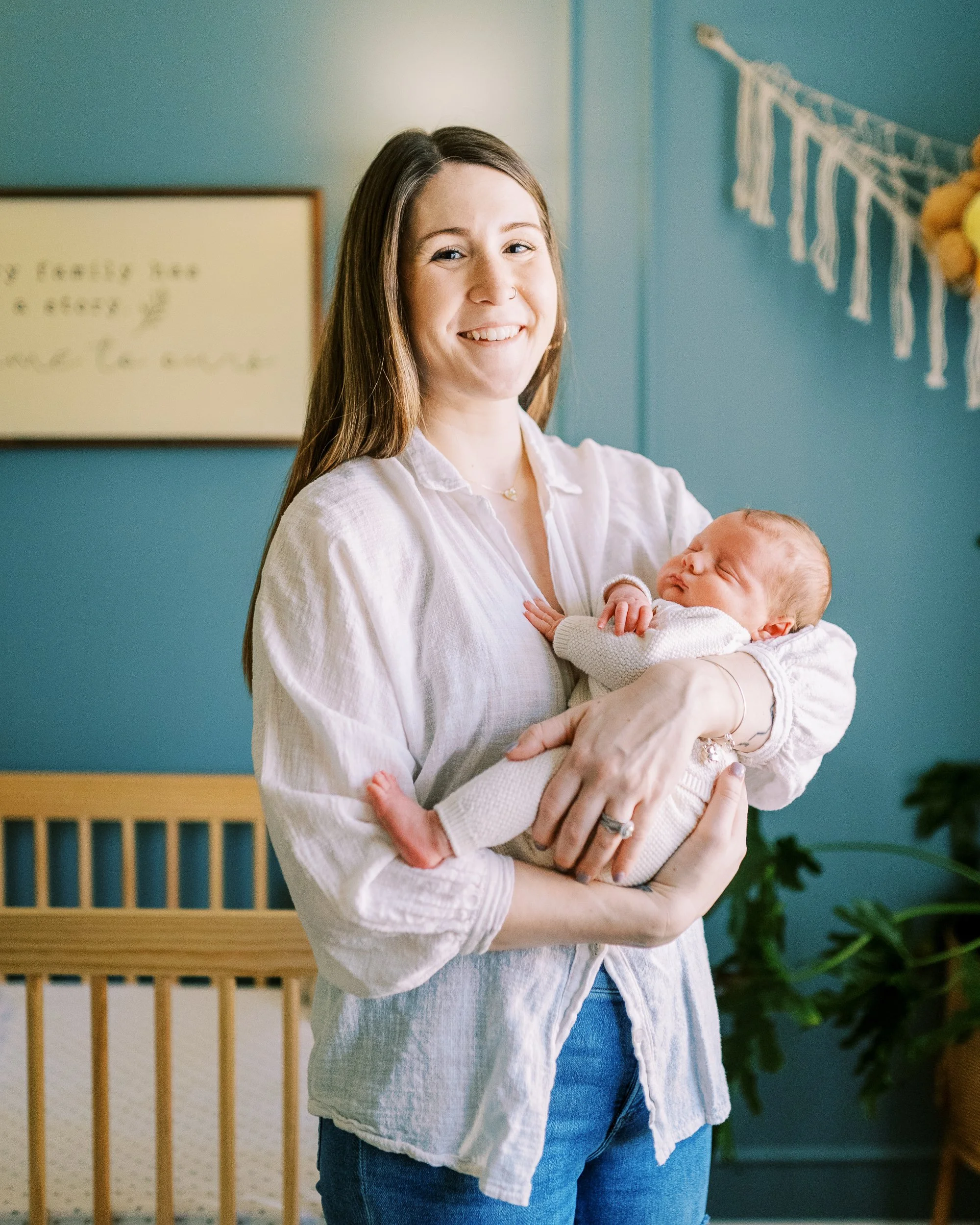 Mother smiling down at her newborn baby with eyes open, standing in the nursery, Roswell, Georgia