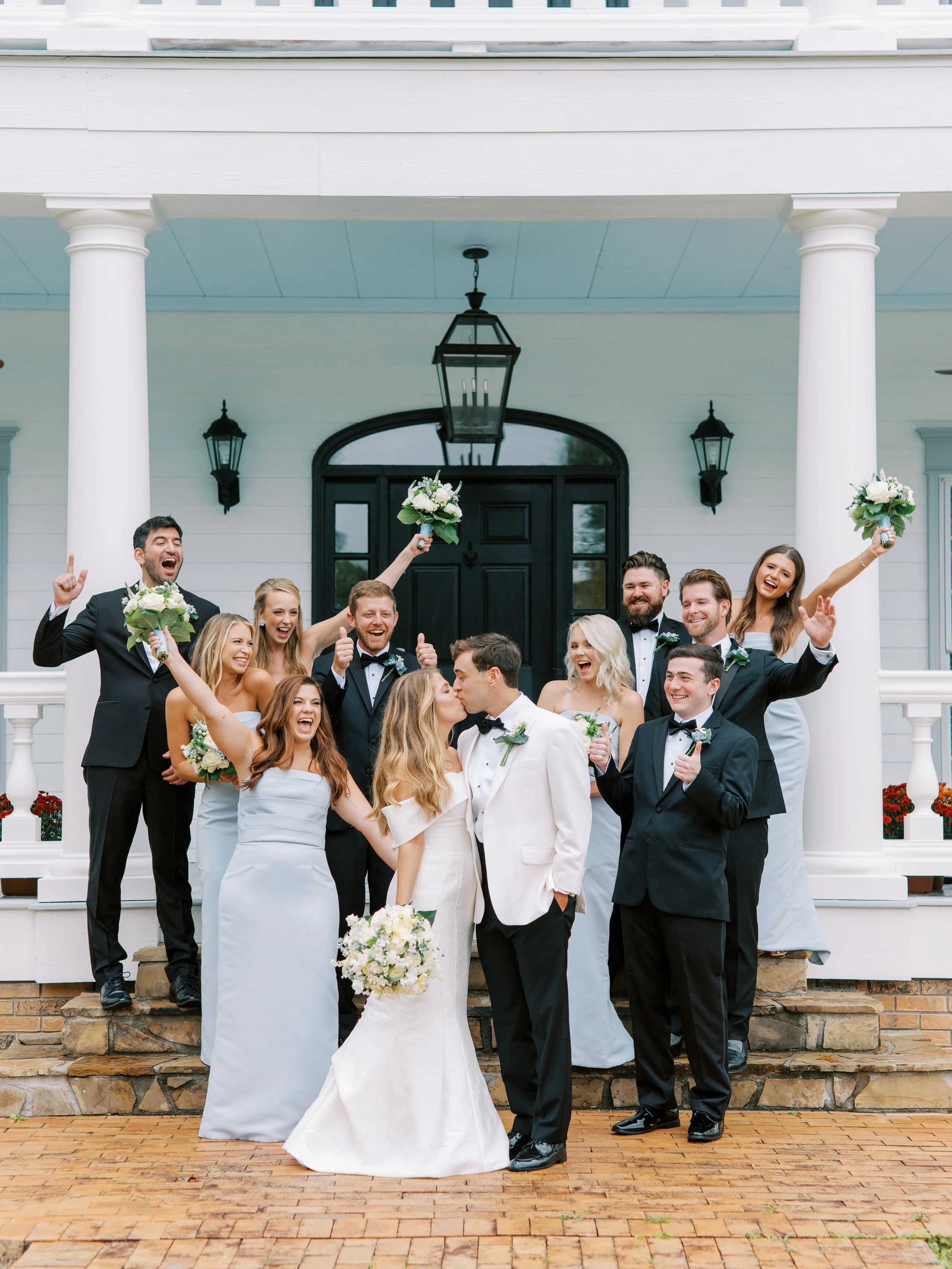 Wedding party celebrating joyfully in front of the plantation house