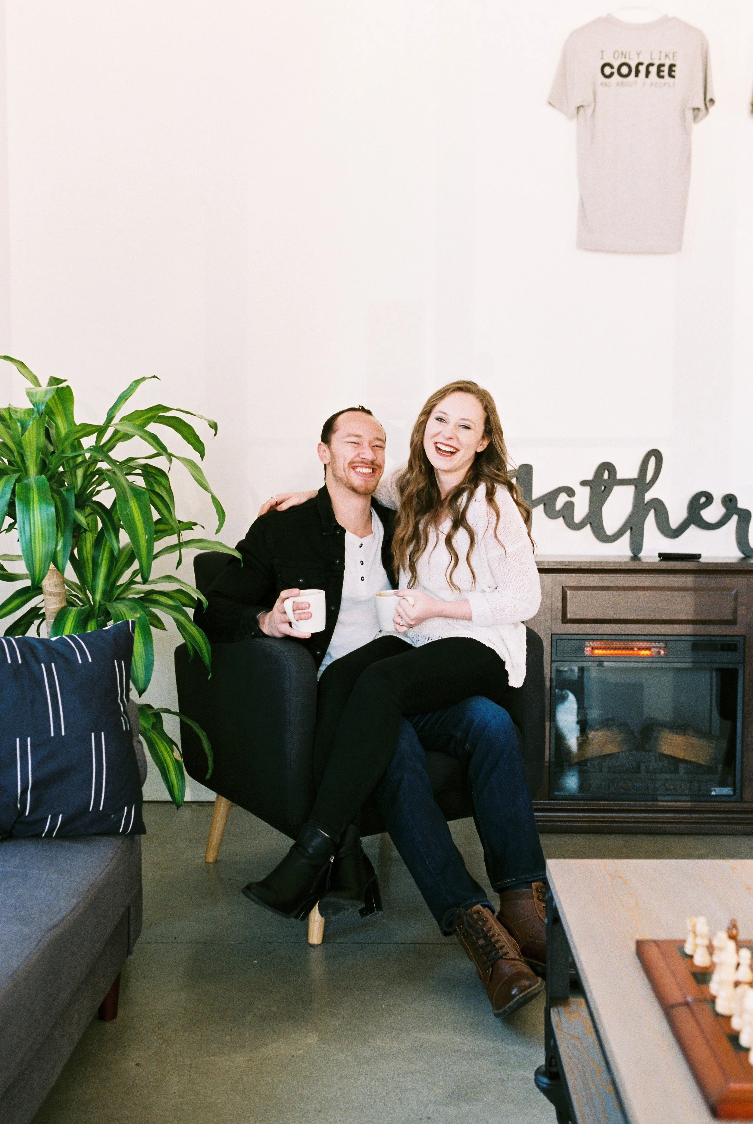 Conner and Maddie laugh together squeezed into one armchair near the fireplace of a Dallas, Georgia coffee shop.