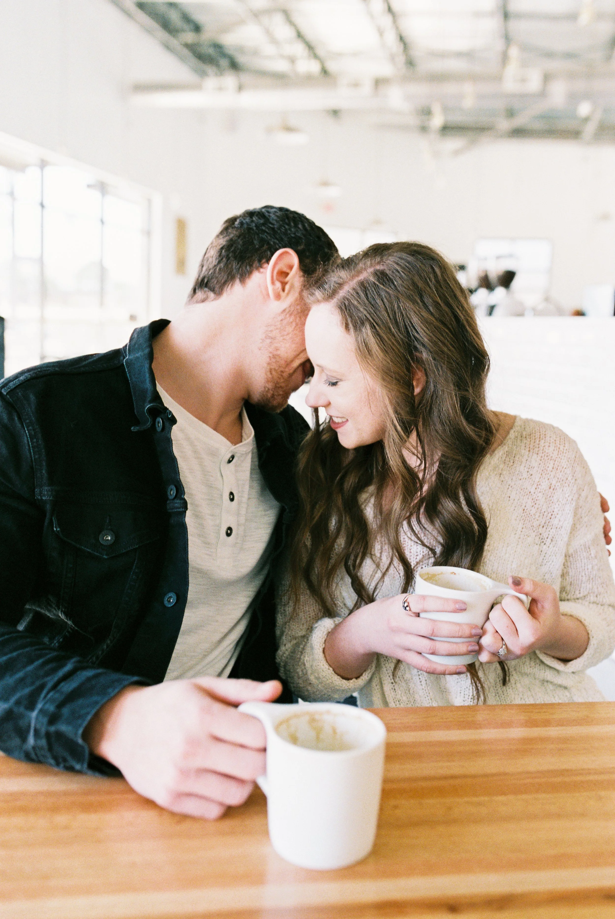 Conner and Maddie lean in close with their coffee mugs on the table in a Dallas, Georgia coffee shop.
