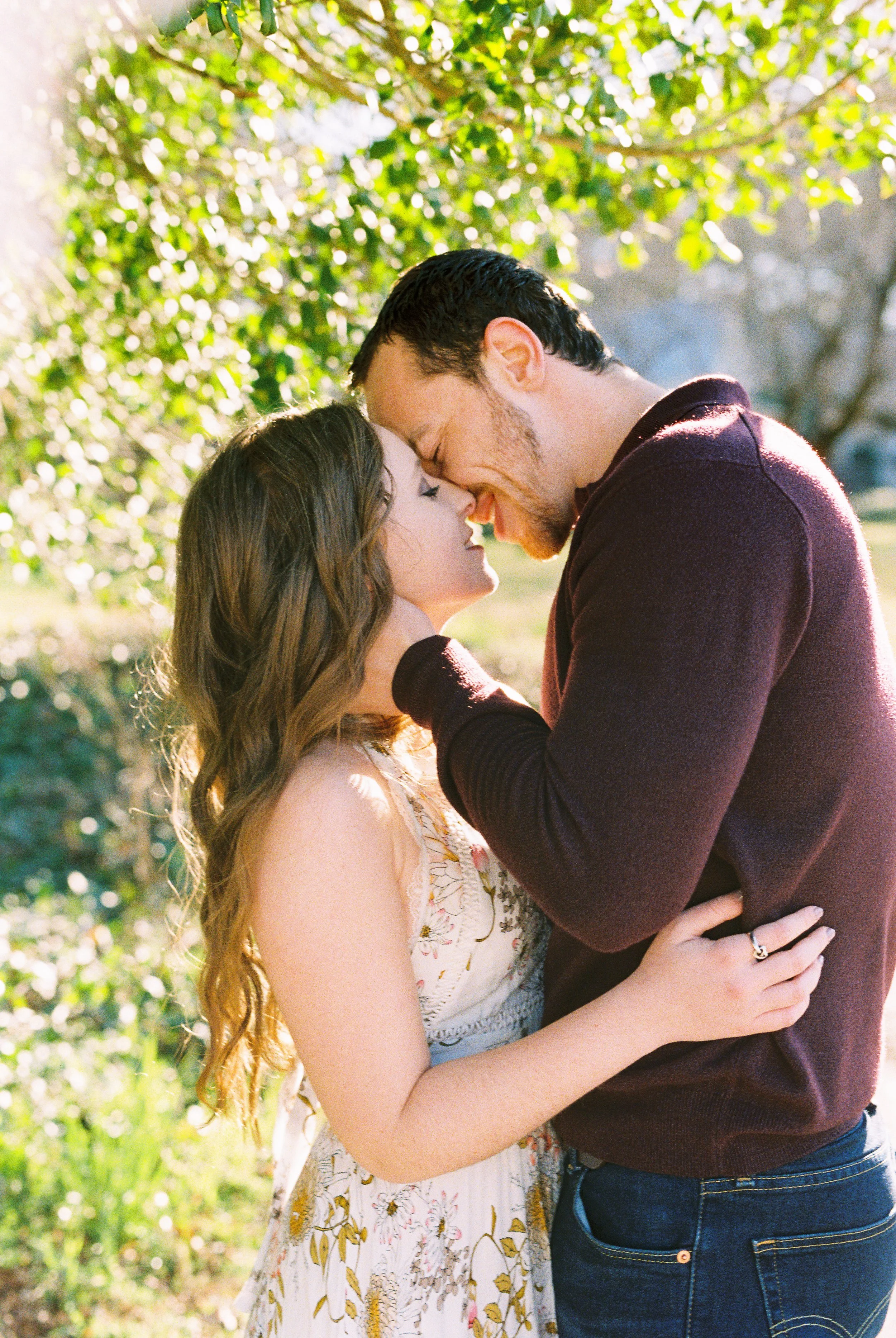 Conner and Maddie embrace forehead to forehead beneath dappled tree light in Dallas, Georgia.