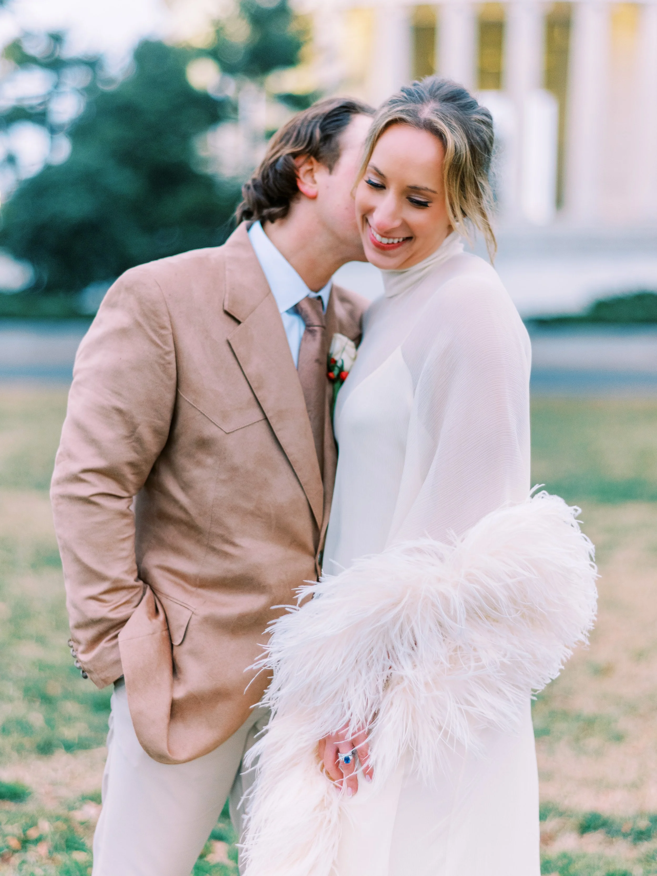 Groom nuzzling the laughing bride's cheek on the memorial lawn