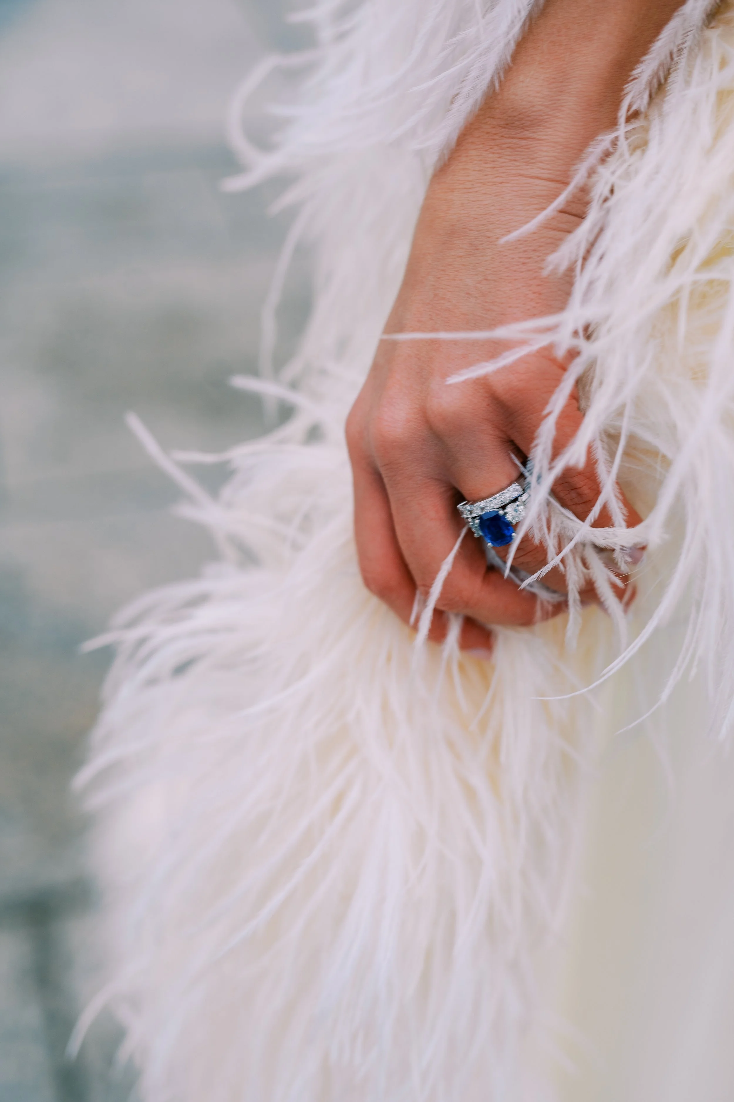 Close-up of the bride's sapphire engagement ring against her fur coat