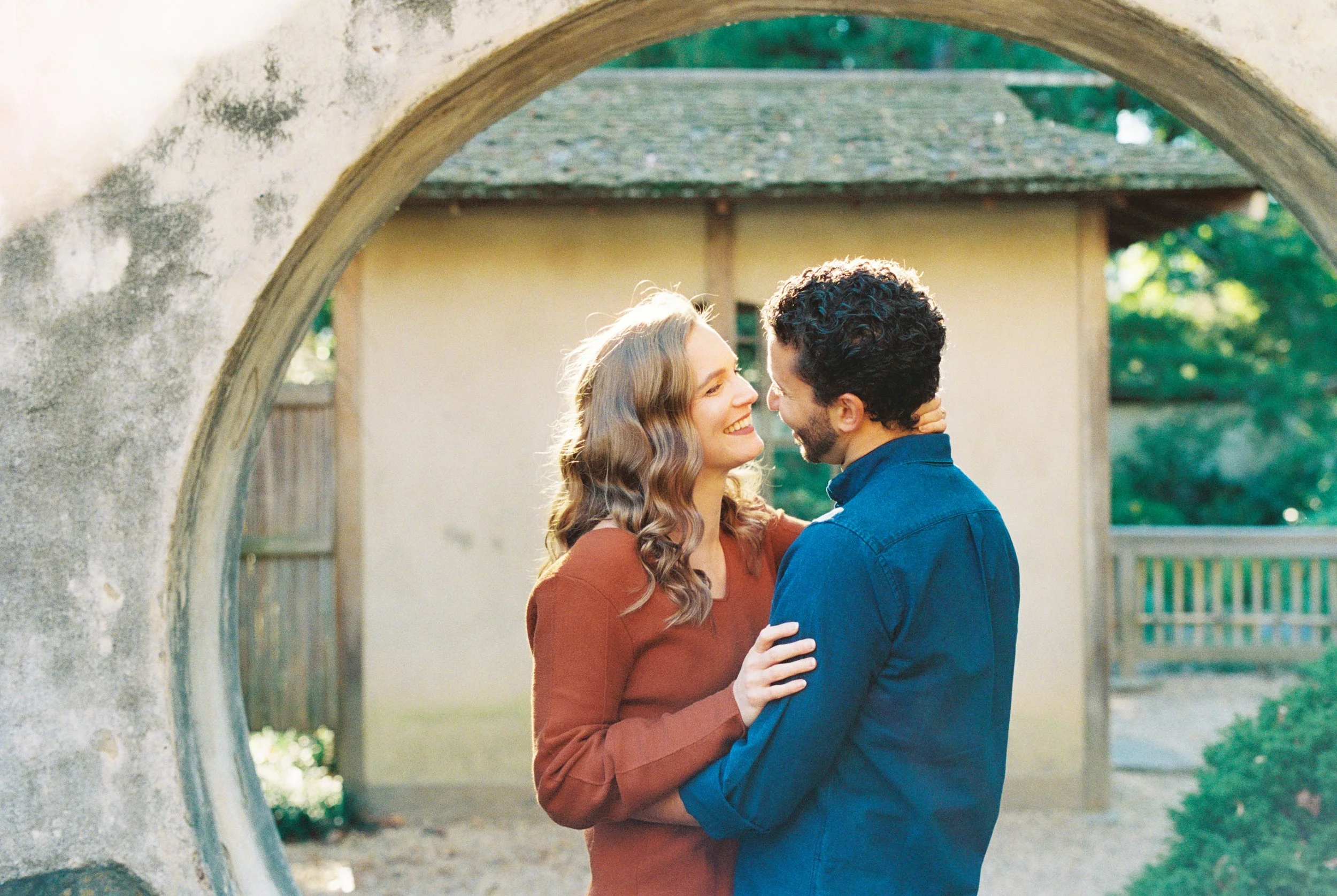 Couple embracing face to face inside a circular garden gate