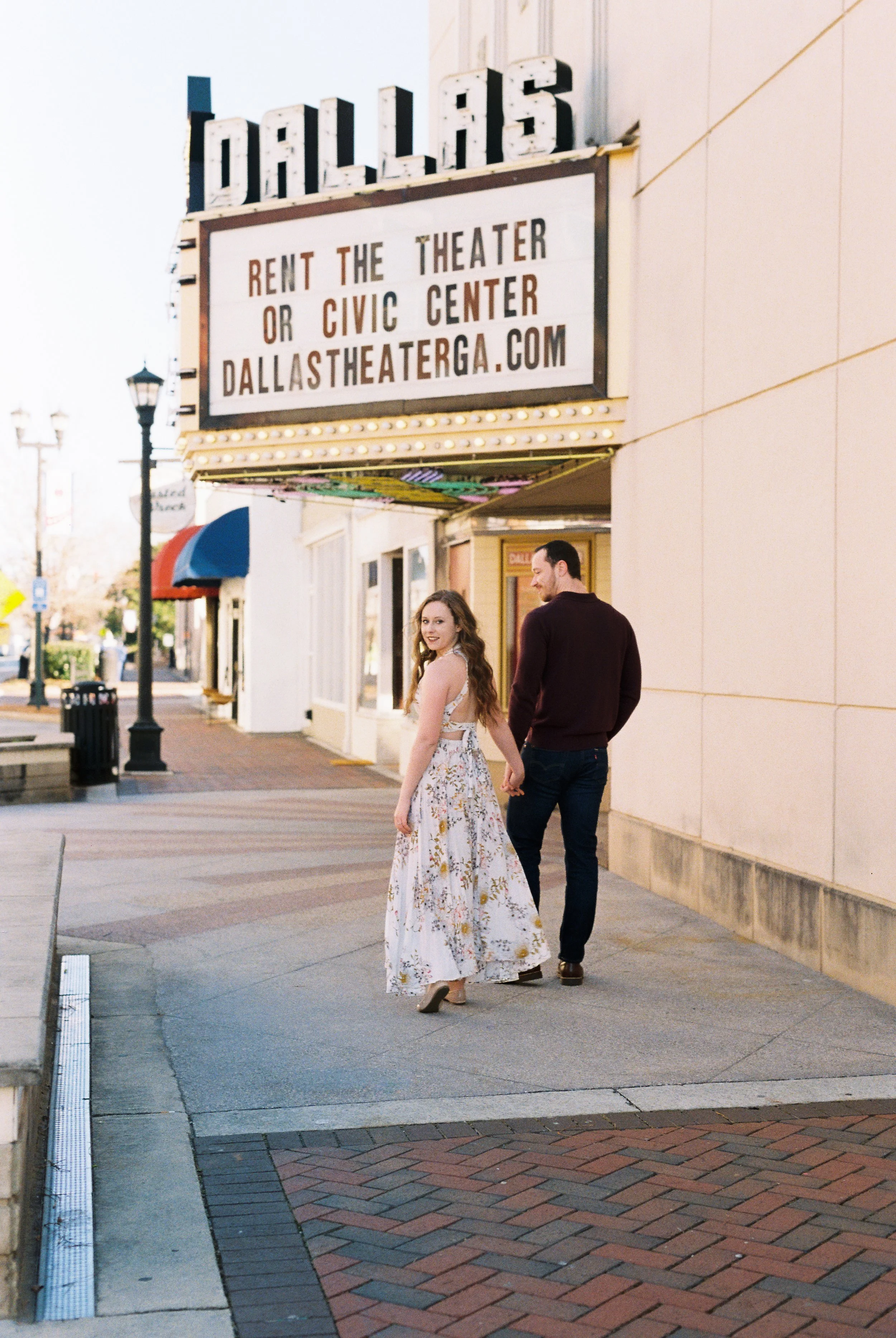Maddie looks back over her shoulder as she and Conner walk hand in hand beneath the Dallas Theater marquee in Dallas, Georgia.