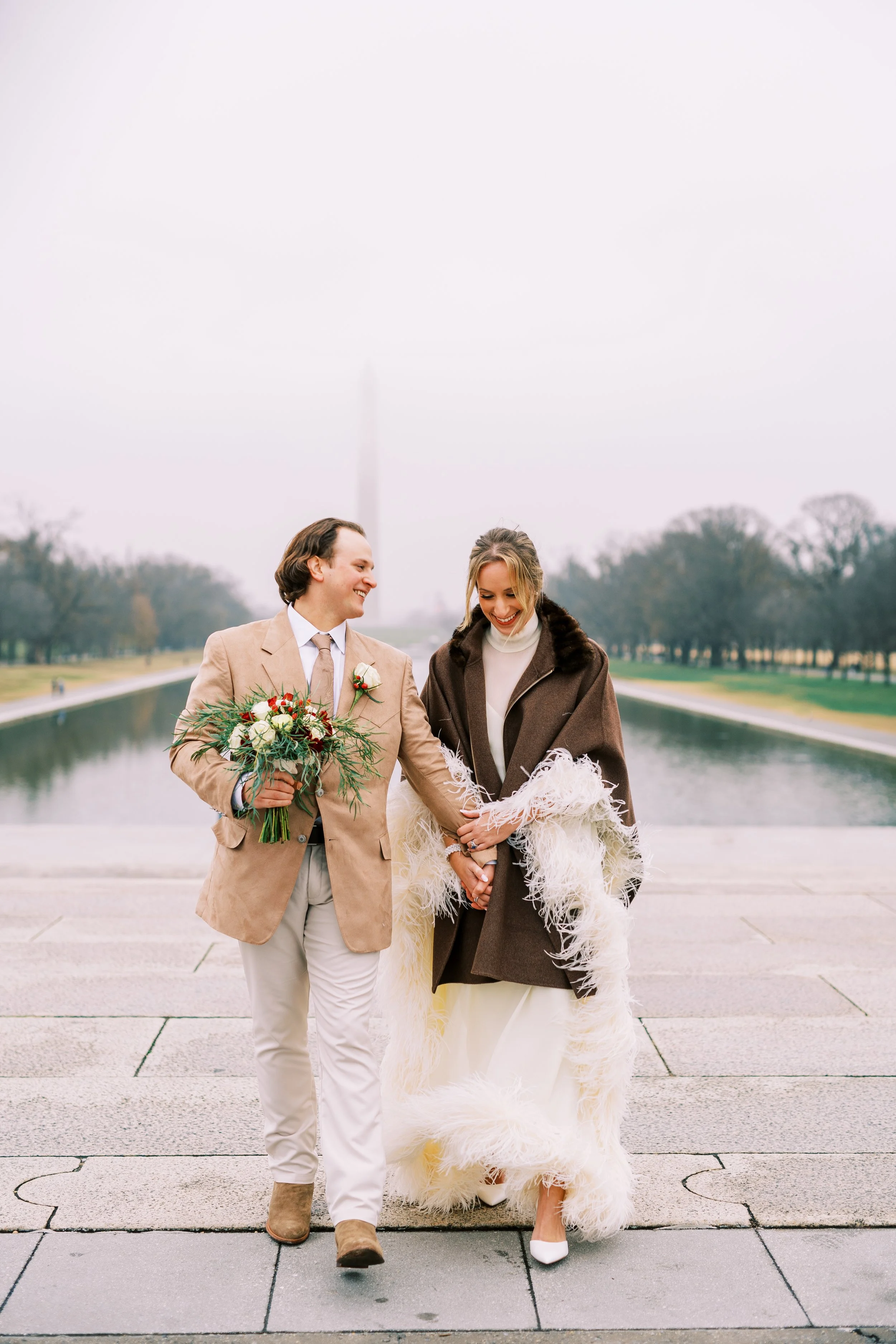Bride and groom embracing on the reflecting pool walkway with the Washington Monument in the distance
