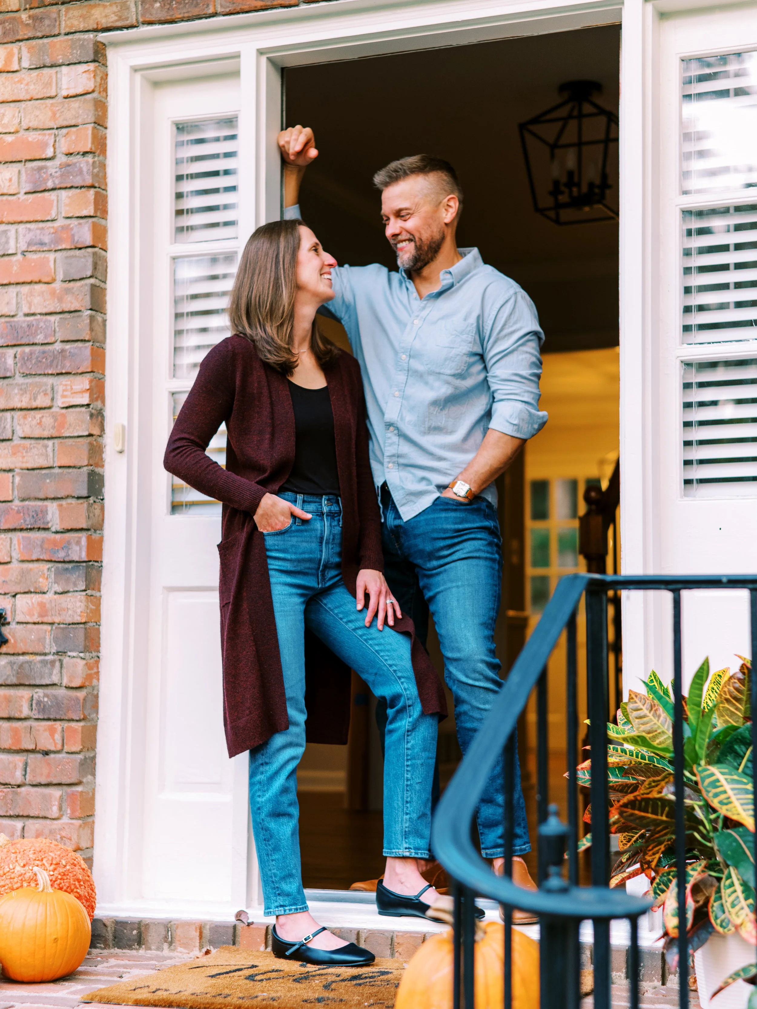 Holly and Chris standing together on their front porch decorated with a pumpkin in Dunwoody, Georgia