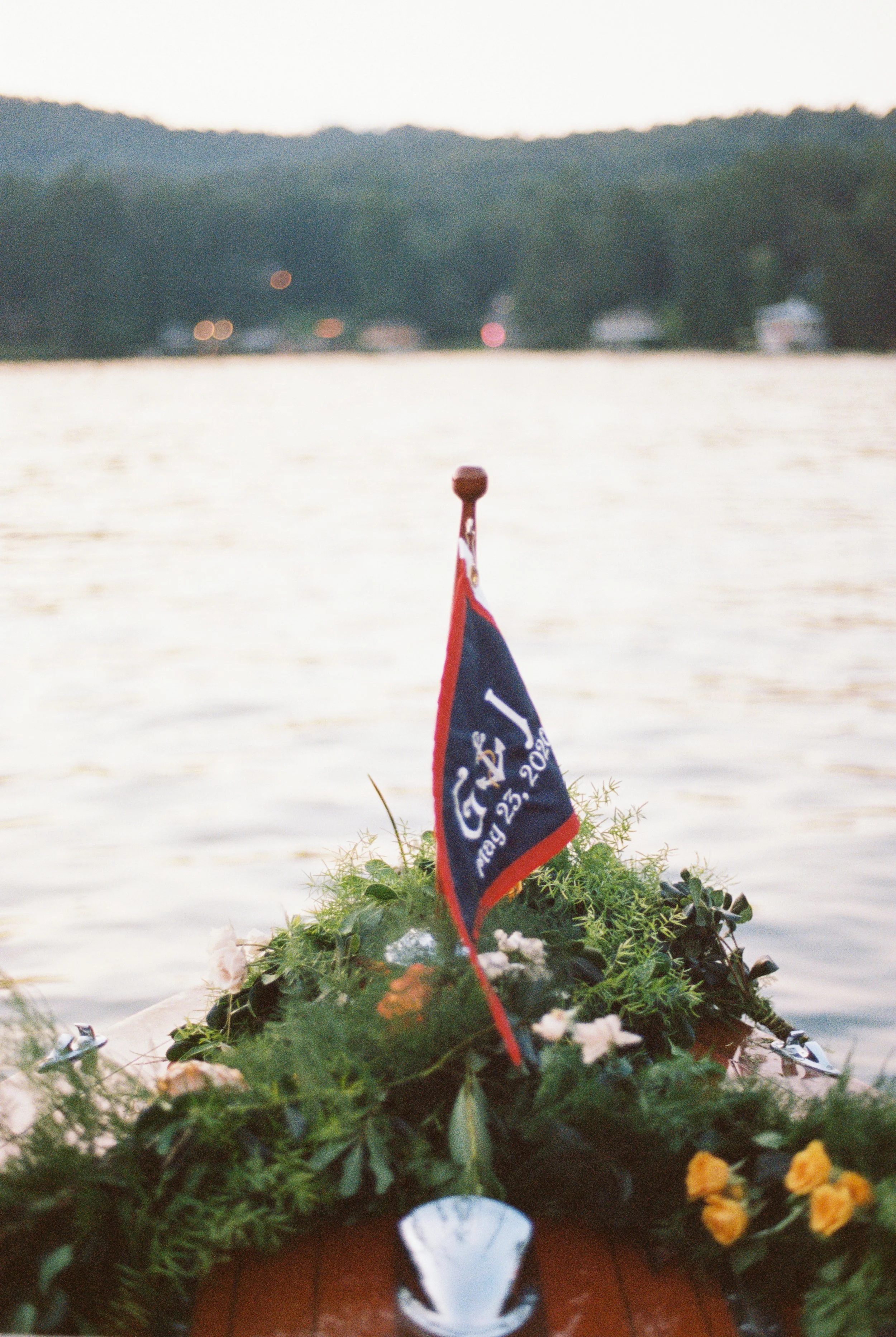Bow of the wedding boat decorated with a small flag and yellow floral arrangement, lake in the background