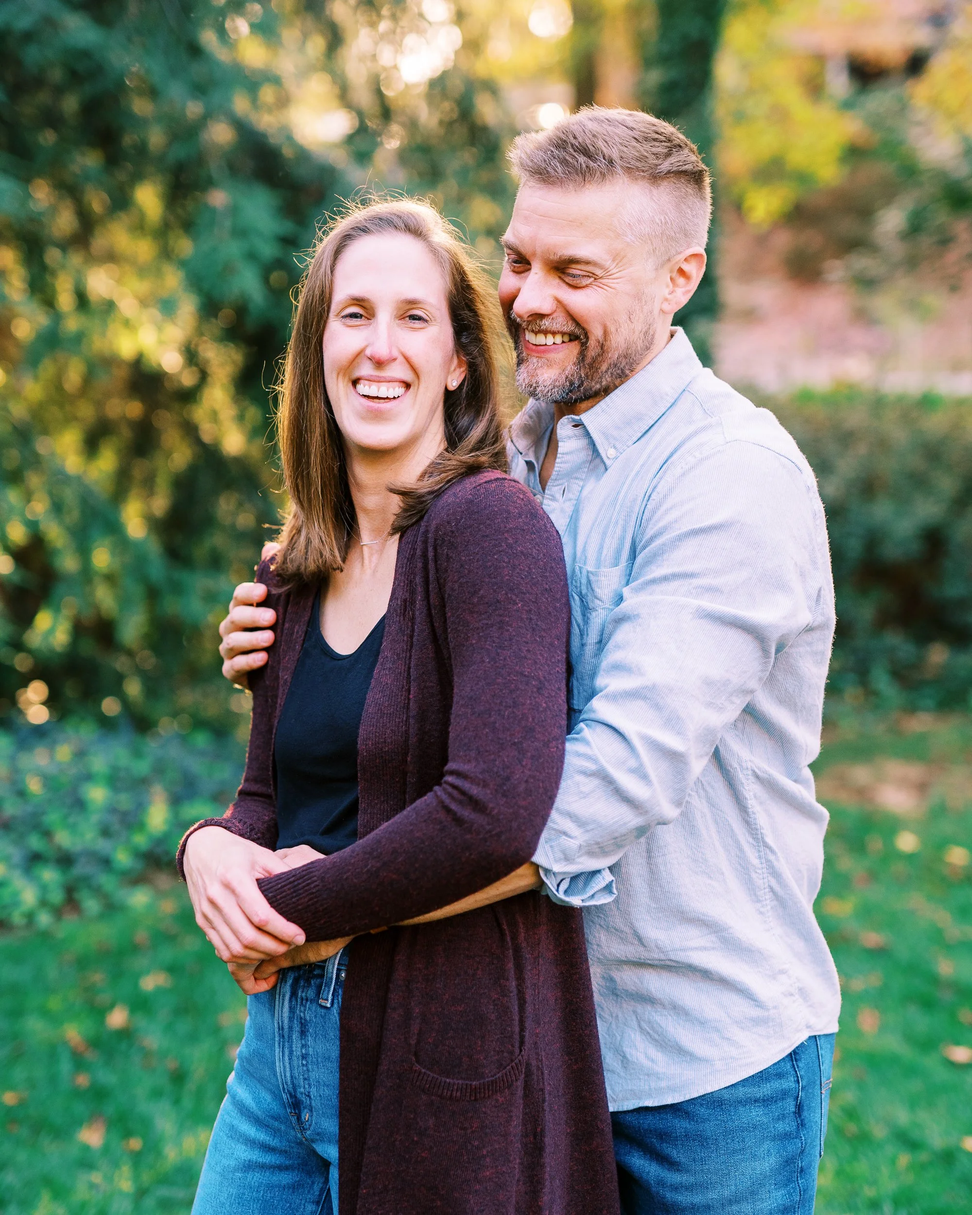 Chris embracing Holly from behind as they smile outdoors in Dunwoody, Georgia