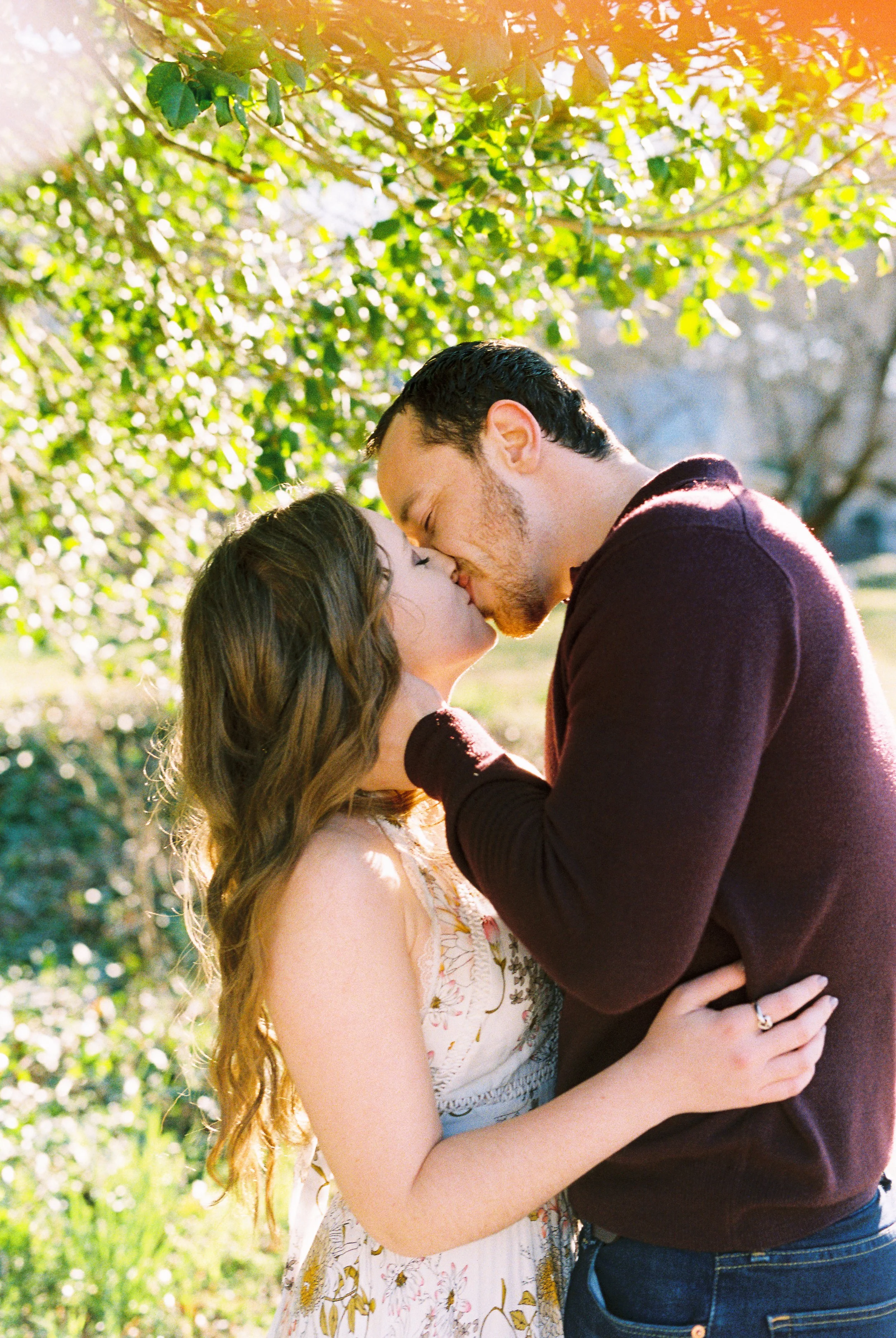 Conner and Maddie kiss under sunlit tree branches in Dallas, Georgia.