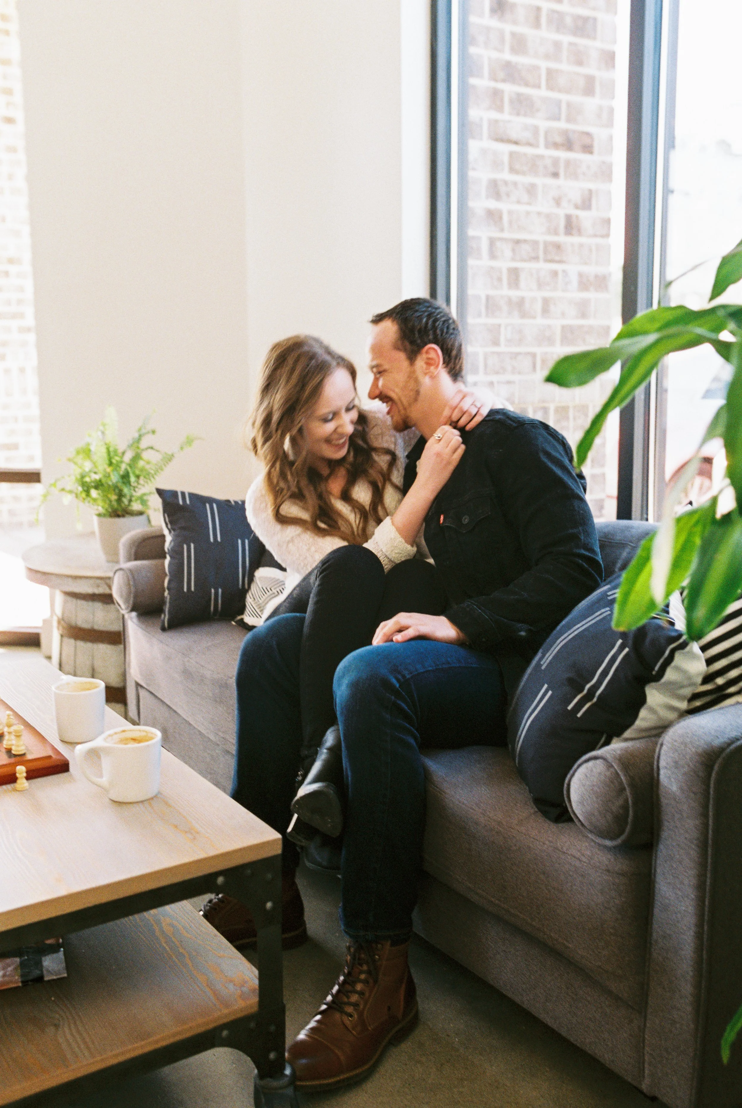 Maddie touches Conner's collar as they laugh together on a couch in a Dallas, Georgia coffee shop.